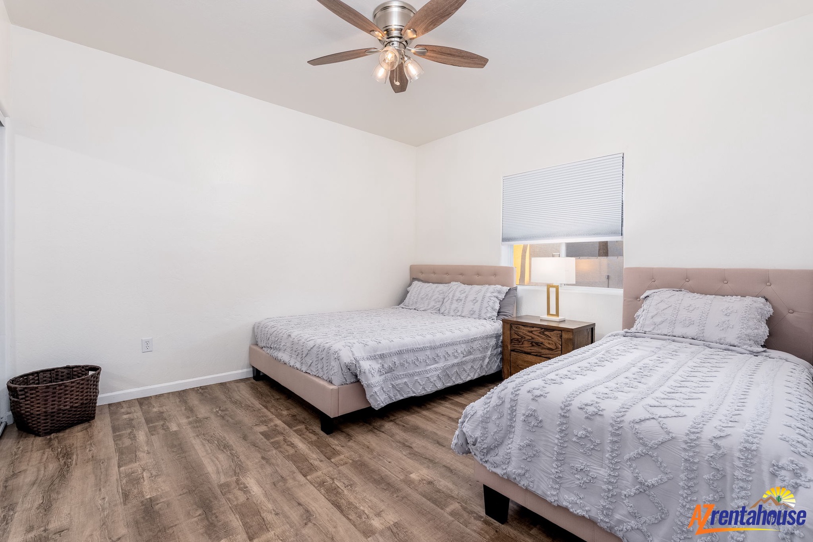 Two cozy beds dressed in soft linens welcome you to unwind after a day of exploring, with a warm ceiling fan gently circulating fresh air overhead.