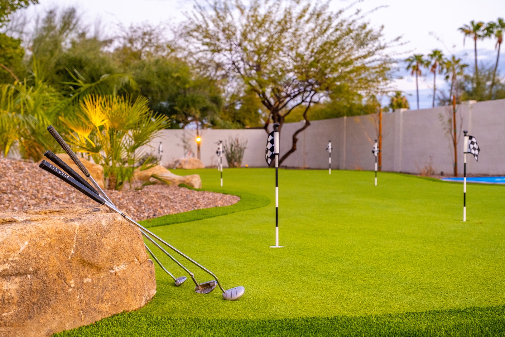 A private putting green awaits, complete with clubs and multiple holes for practicing your short game surrounded by desert landscaping and palm trees.