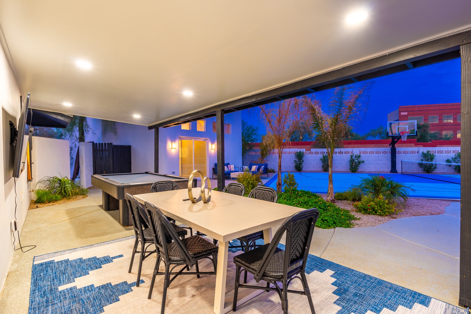 The covered patio opens onto a private court with a pool table and dining for six, plus a basketball hoop awaits outside for friendly competition.