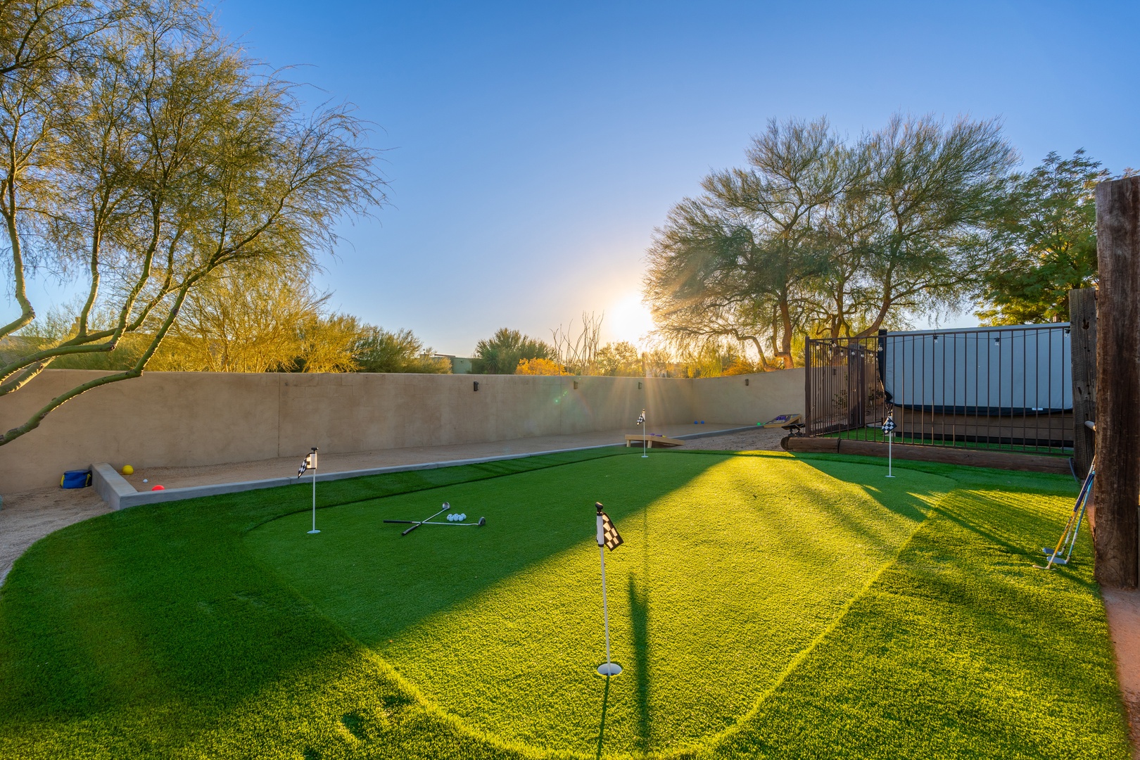 The property features a private putting green surrounded by desert trees, perfect for practicing your golf game under the Arizona sky at sunrise or sunset.