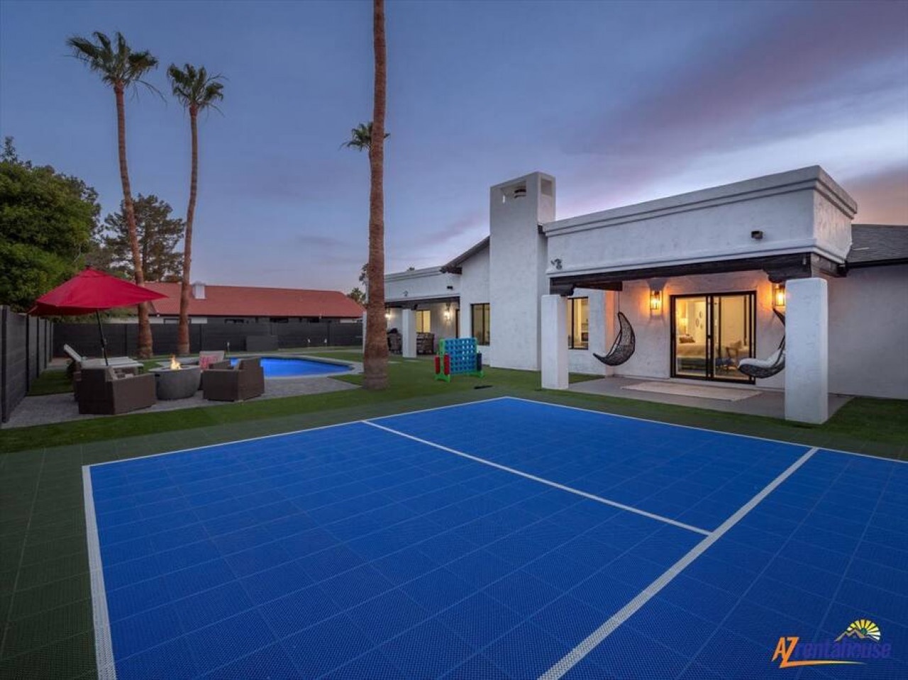 Modern desert retreat featuring sport court, pool, and outdoor entertainment areas surrounded by palm trees.