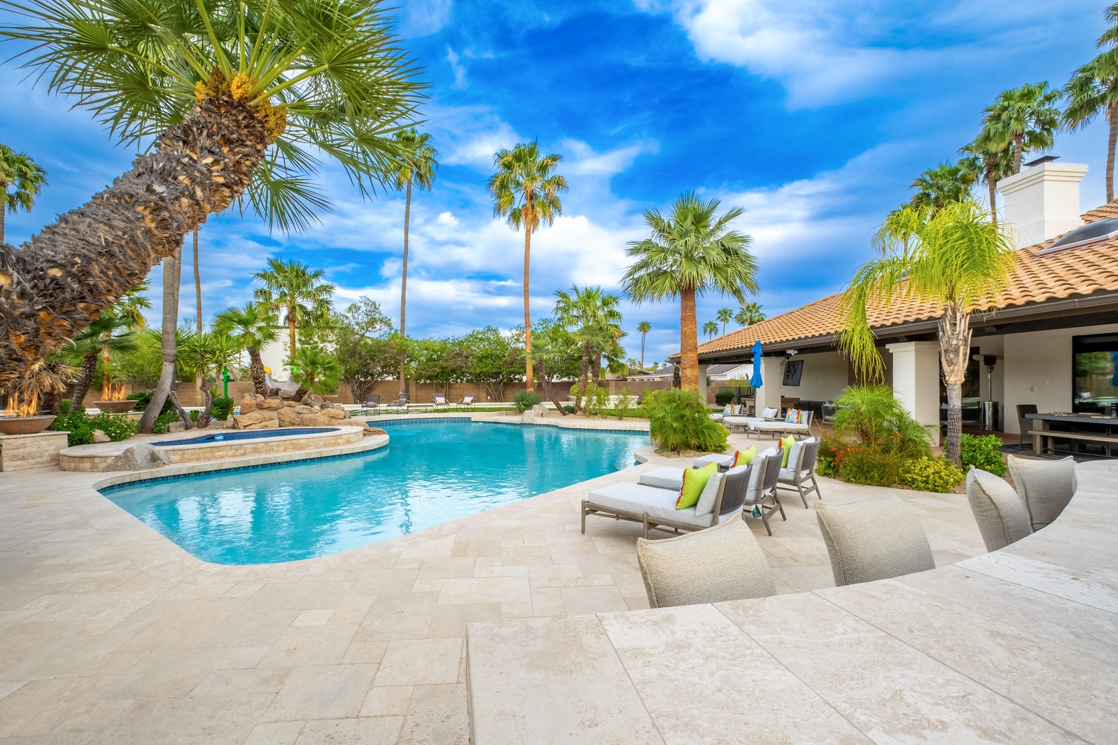 A resort-style pool oasis featuring a luxurious swimming area, spa, and inviting loungers under swaying palms—your private escape beneath endless blue skies.