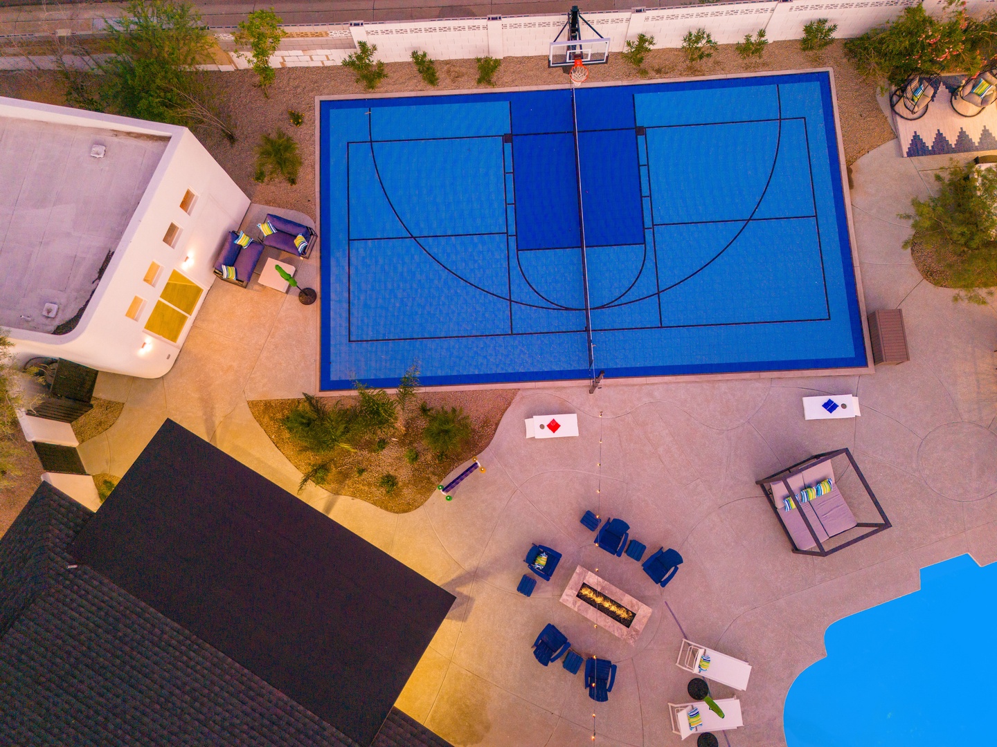Aerial view of the property features a full-size basketball court, outdoor seating areas with fire pit, and recreation zones surrounded by desert landscaping.