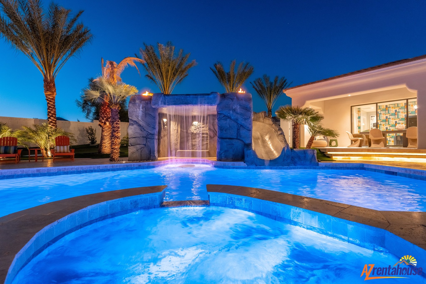 Stunning resort-style pool with waterfall, hot tub, and tropical palms creates your private oasis under the desert stars.
