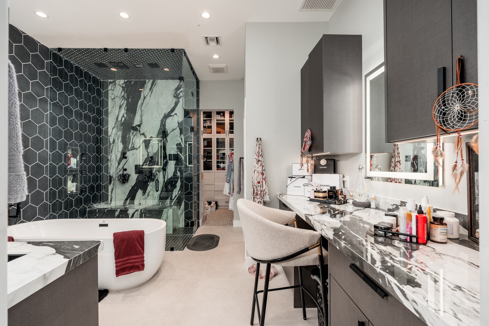 Luxurious spa-inspired bathroom with striking marble finishes, a freestanding soaking tub, and a stunning black hexagonal-tiled walk-in shower—your private sanctuary awaits.