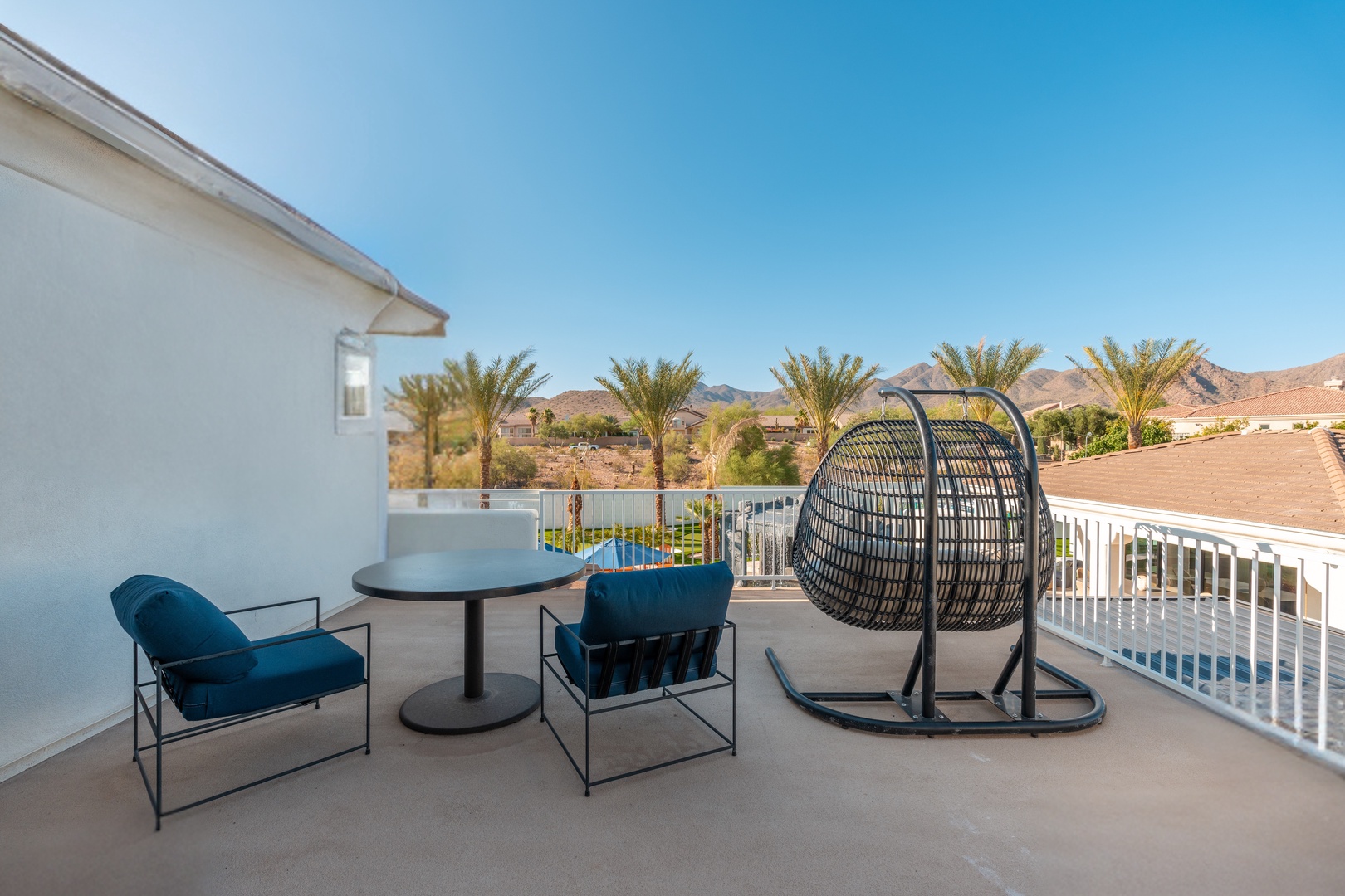 Soak up desert views from your private balcony with stylish seating and a cozy hanging chair overlooking palm trees and mountains.