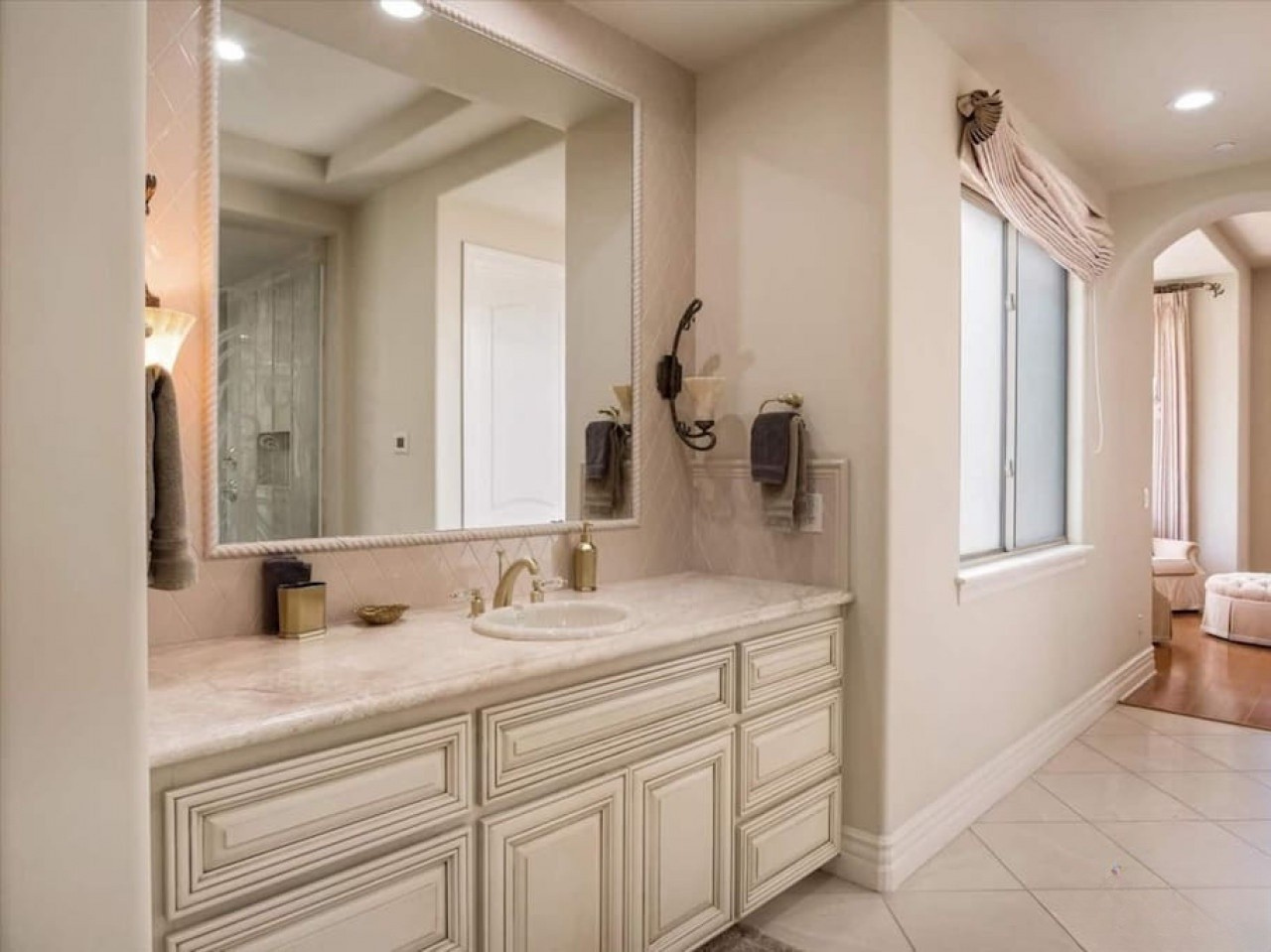 Step into your private spa-like retreat with marble countertops, elegant cabinetry, and soft natural light pouring through the window, creating a serene sanctuary for your daily routines.