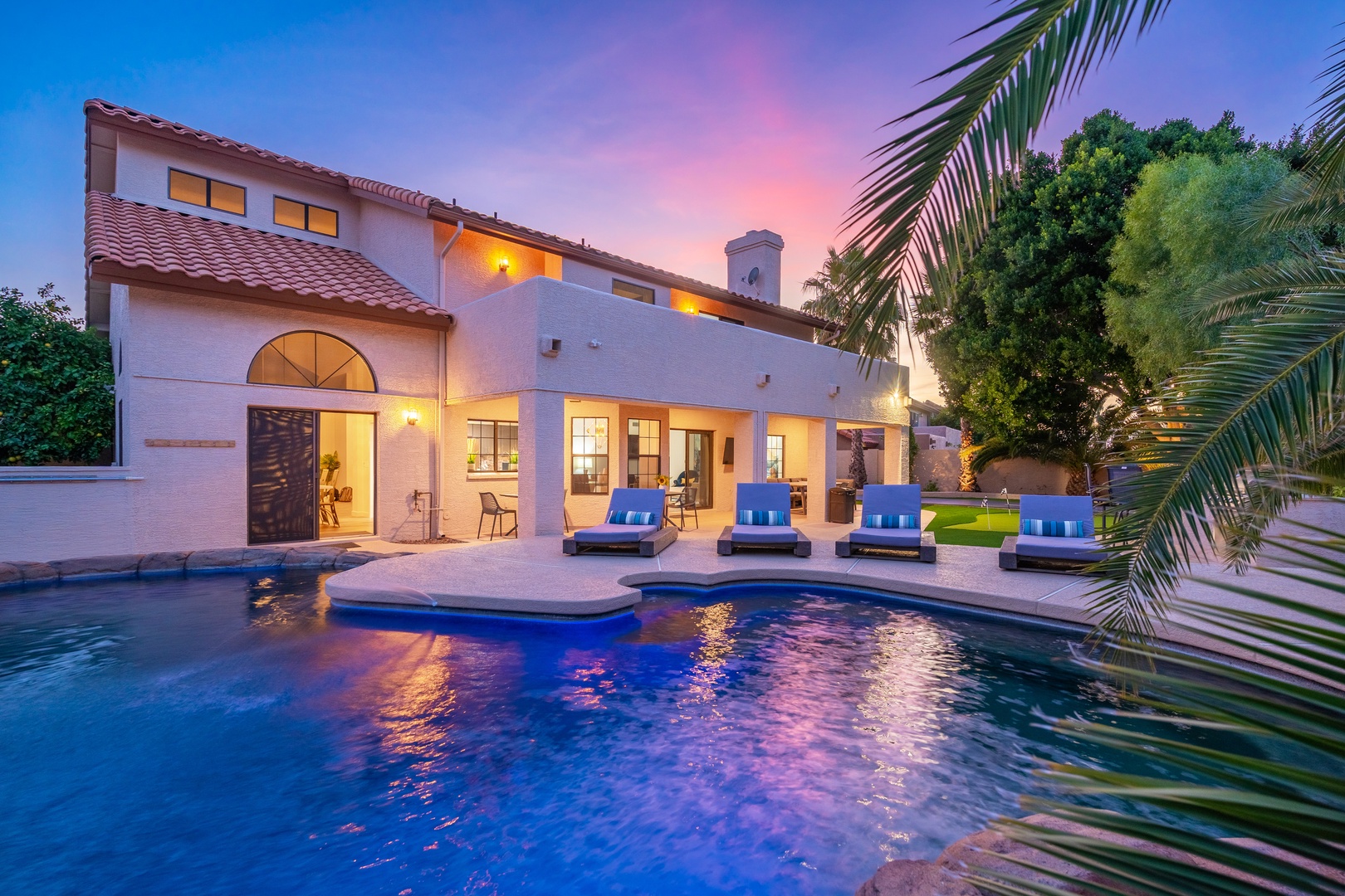 Stunning Mediterranean-style villa with private pool and spacious patio, framed by lush palms under a breathtaking twilight sky—an idyllic desert retreat awaits.