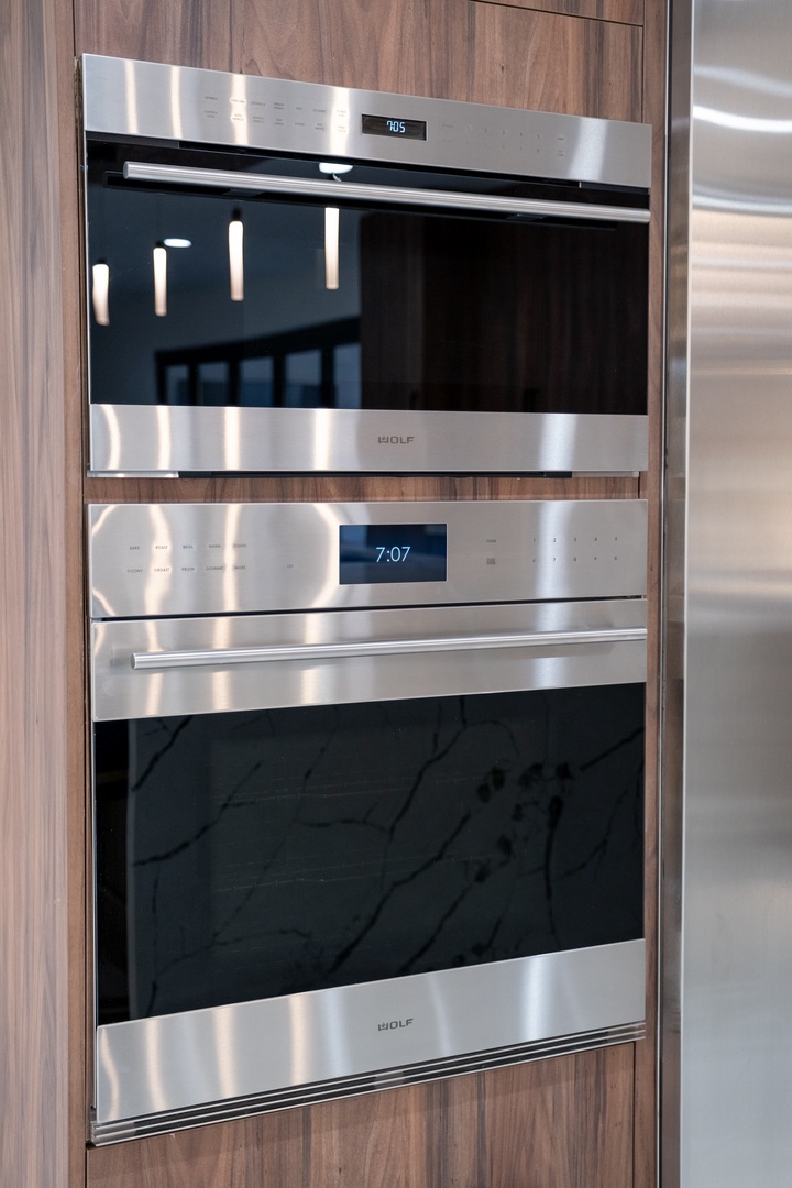 High-end built-in Wolf oven and microwave combo seamlessly integrated into sleek wood cabinetry, ready for your culinary creations during your stay.