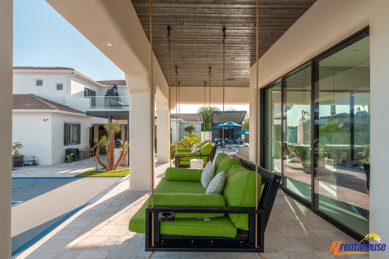 Unwind on your private covered terrace with plush green seating, perfect for morning coffee or evening relaxation while enjoying poolside views.