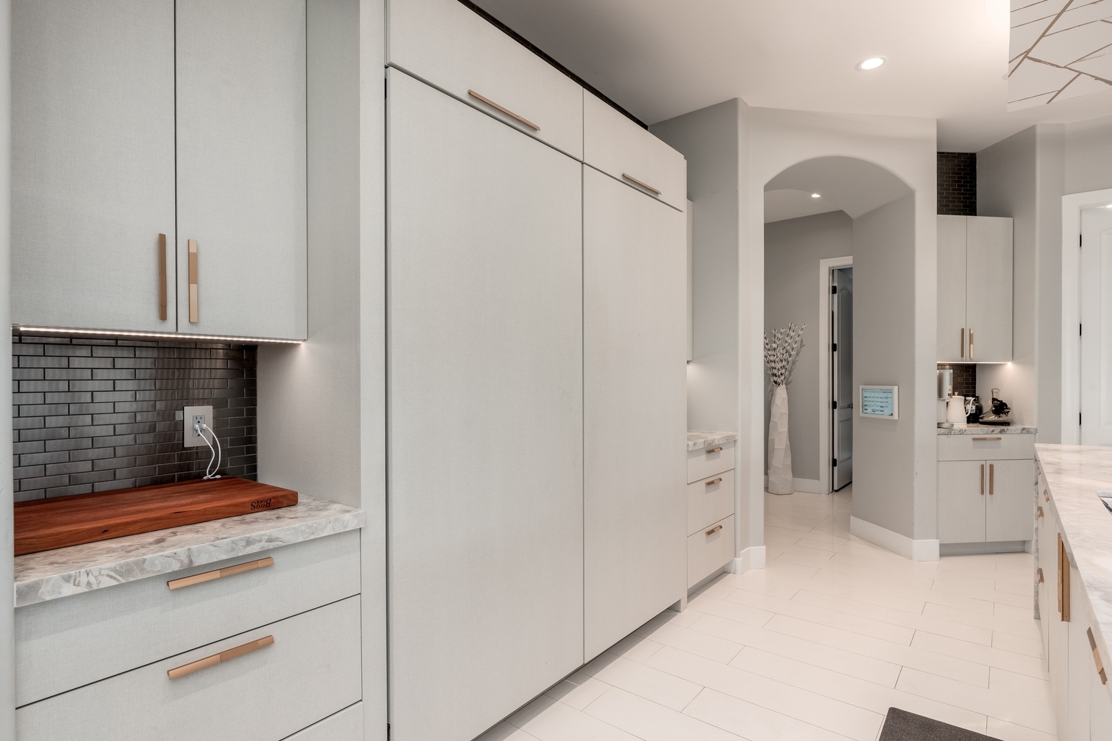 Bright, modern kitchen awaits with gleaming white cabinetry, marble countertops, and warm wood accents. You'll love the sleek tile backsplash and open flow into adjoining spaces, perfect for your culinary adventures.