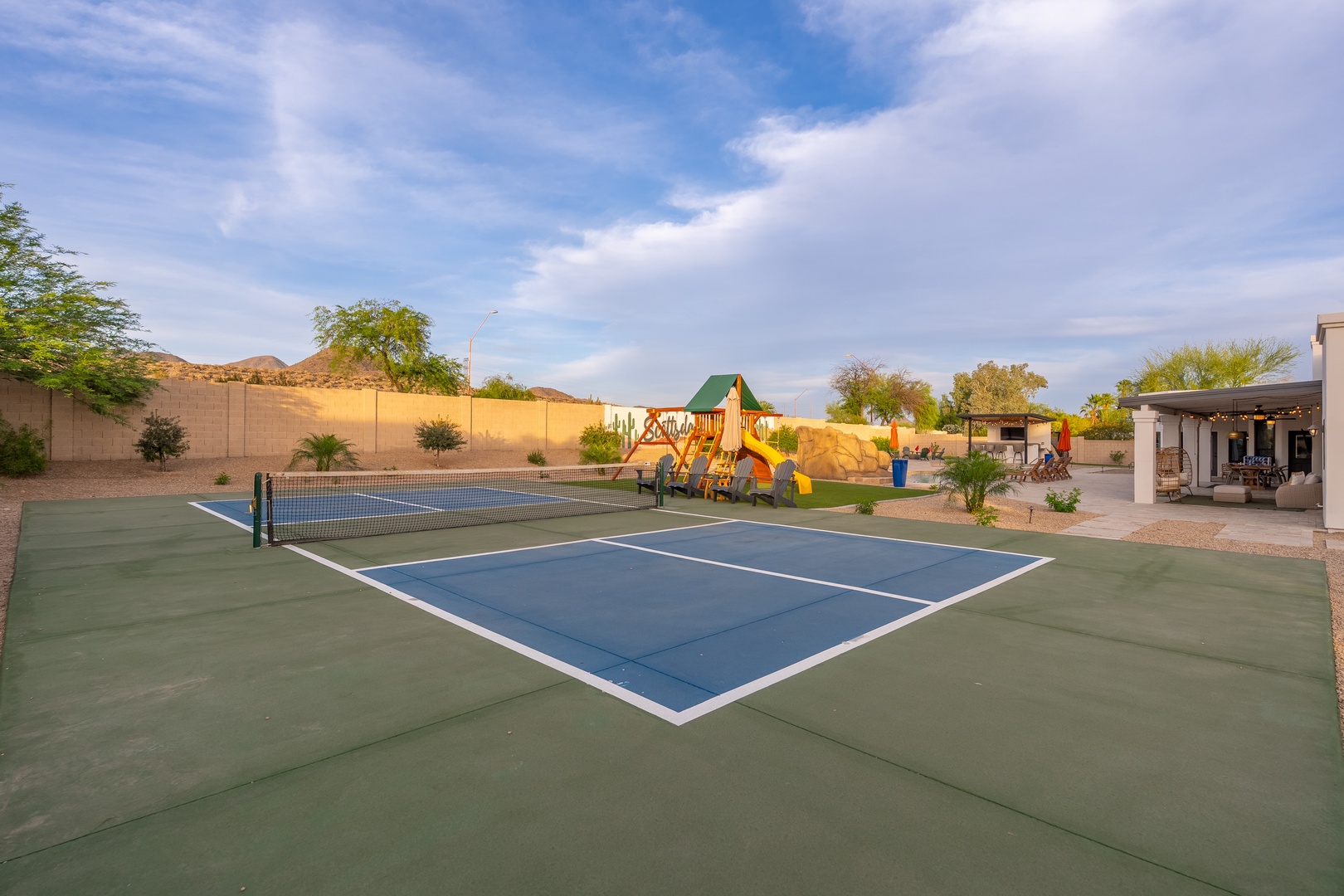 Private tennis court and playground set against desert mountain views, offering active recreation for all ages in a spacious outdoor setting.