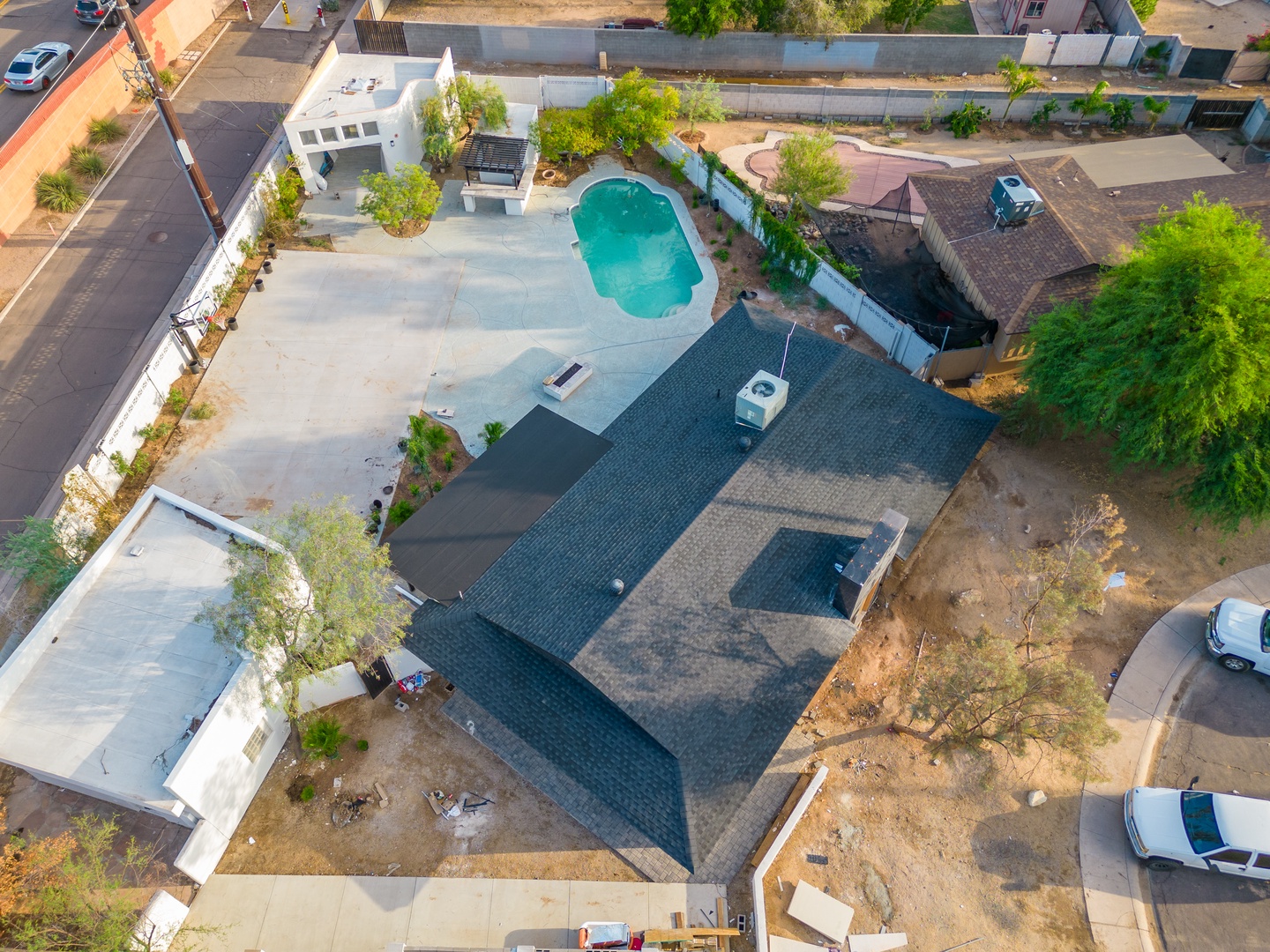 Aerial view of the property featuring a sparkling swimming pool, spacious patio, and ample parking in a quiet residential neighborhood.