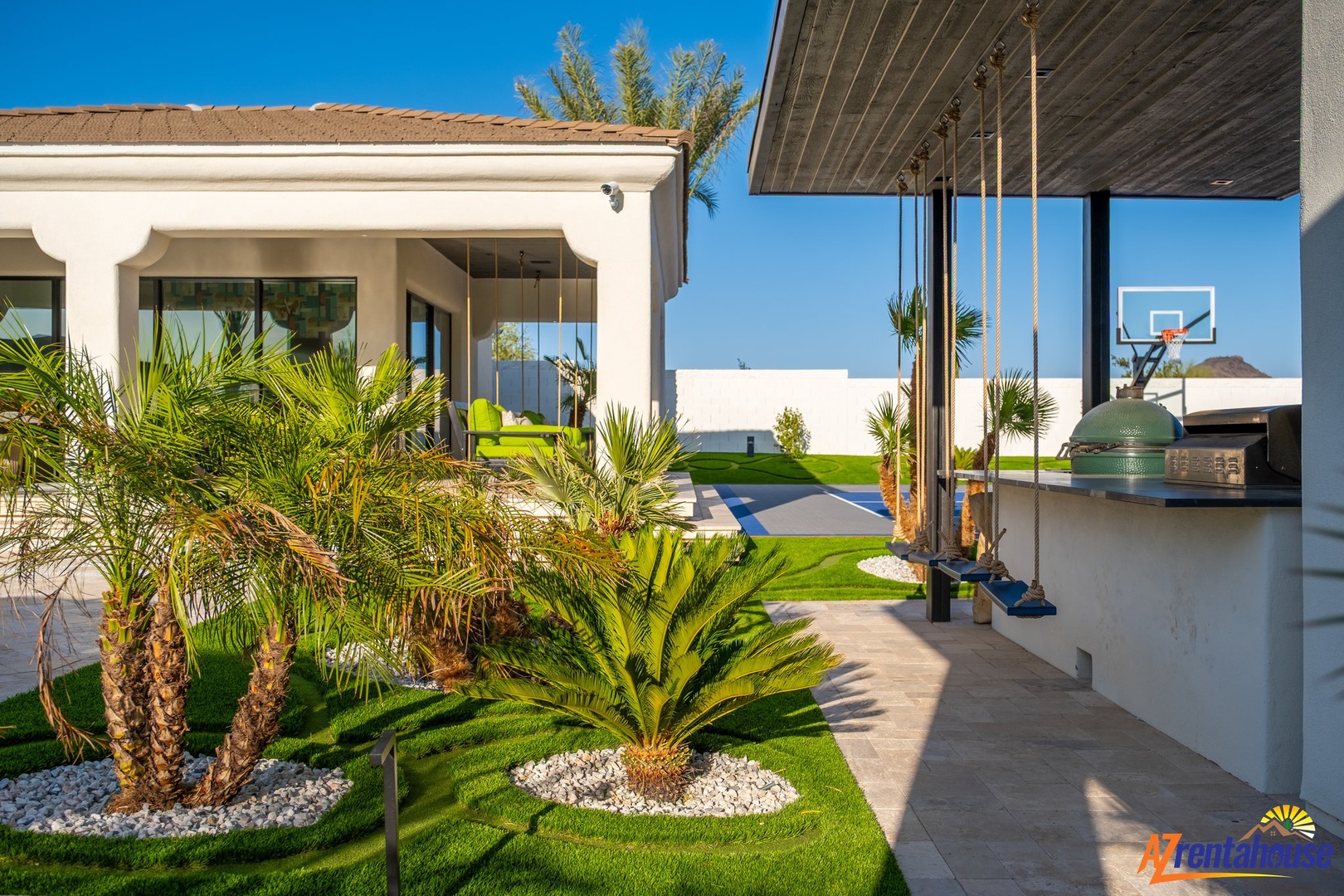 Modern outdoor kitchen overlooking tropical gardens and sports court - perfect for entertaining under sunny skies.