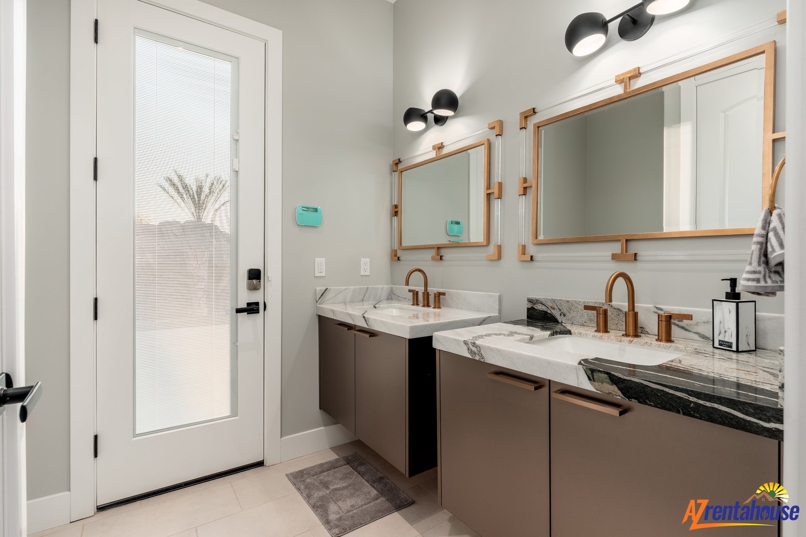 Your sleek en-suite features dual vanities with elegant marble countertops and warm brass fixtures, perfect for your morning routine.