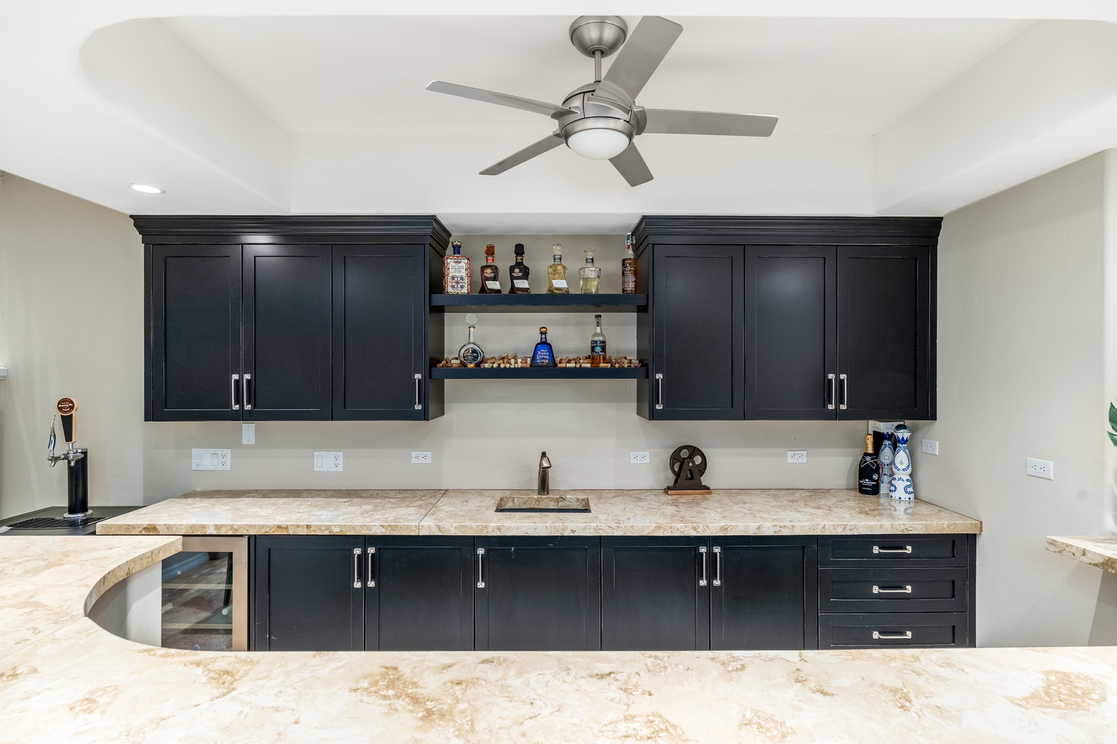 You'll love this stylish wet bar with sleek black cabinetry, marble countertops, and a built-in beverage fridge—perfect for mixing drinks and entertaining guests during your stay.