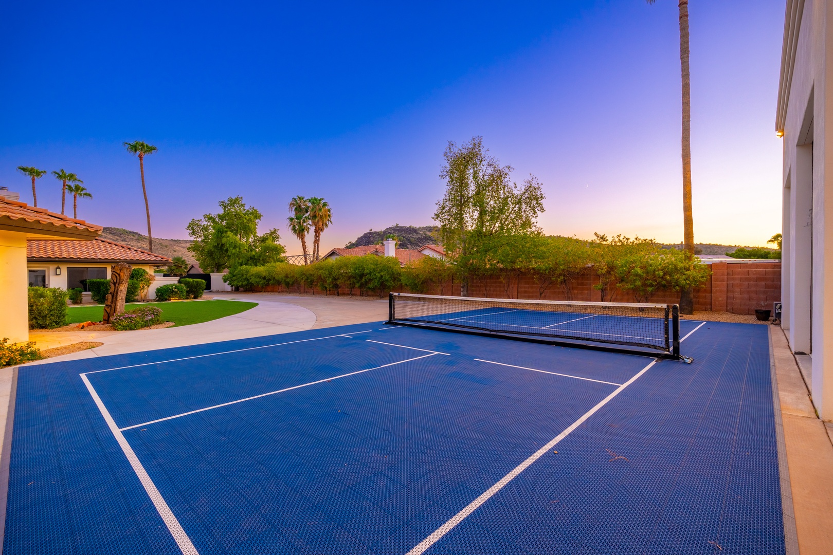 A private tennis court awaits under Arizona skies, framed by palm trees and mountain views—your perfect spot for morning matches or sunset rallies.
