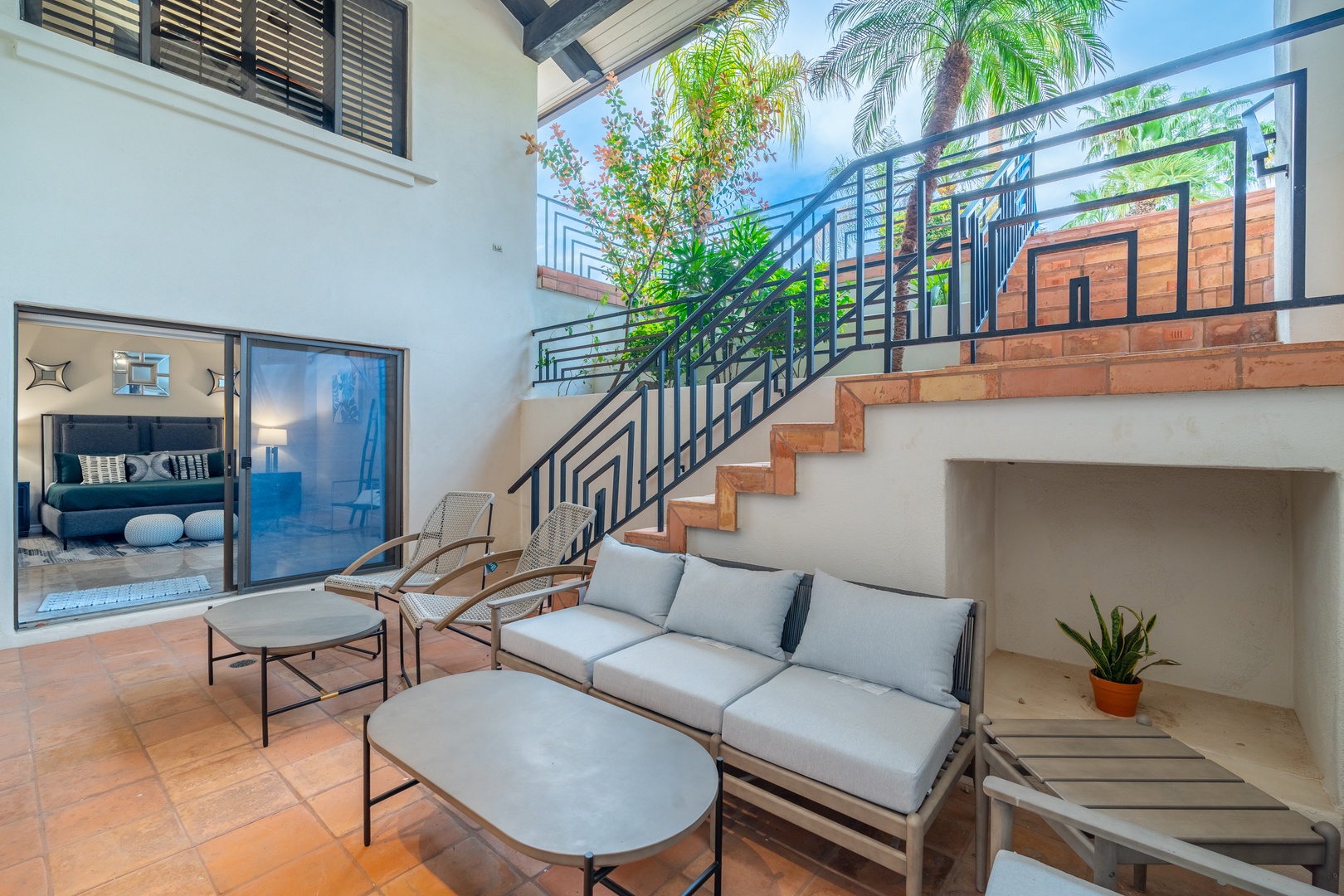 Your private courtyard oasis awaits with stylish lounge seating, lush palms overhead, and direct access to your beautifully appointed suite—perfect for morning coffee or evening relaxation.