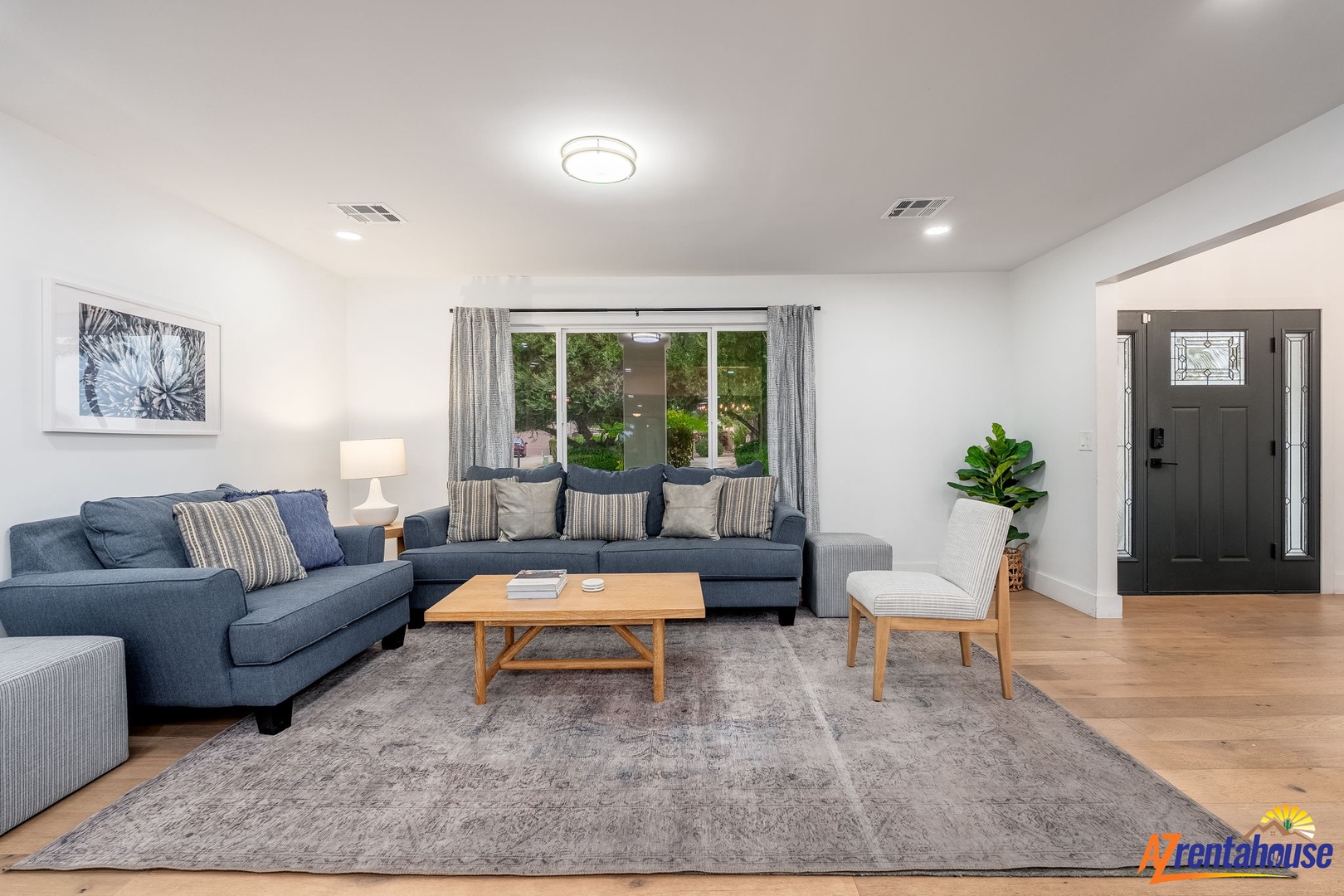 Sink into plush blue sofas in your bright living room, where natural light streams through garden views and modern comfort awaits.
