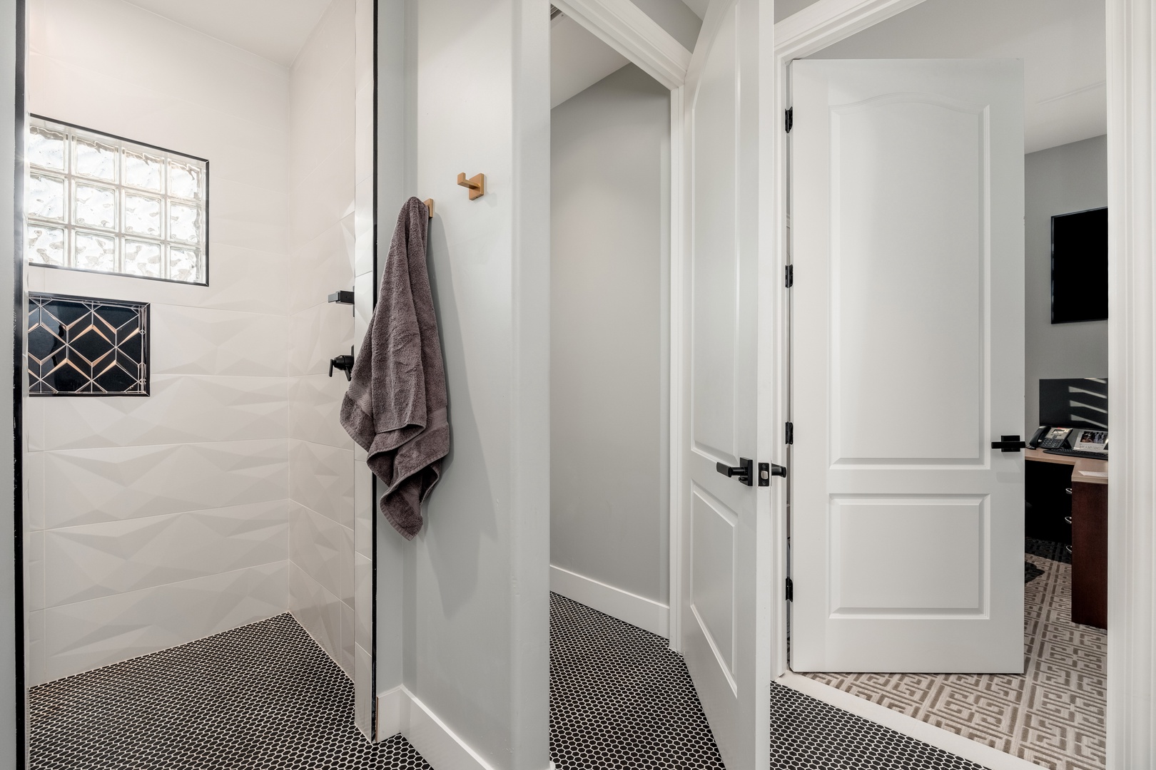 Step into your beautifully appointed bathroom featuring a spacious walk-in shower with elegant white tile, modern black fixtures, and soft natural light—your private retreat for unwinding after exploring.