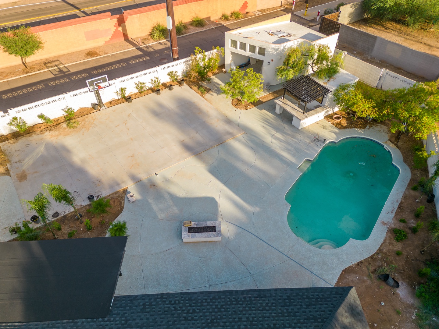 Aerial view of property featuring a private pool, basketball court, covered patio area, and landscaped outdoor spaces in a suburban neighborhood setting.