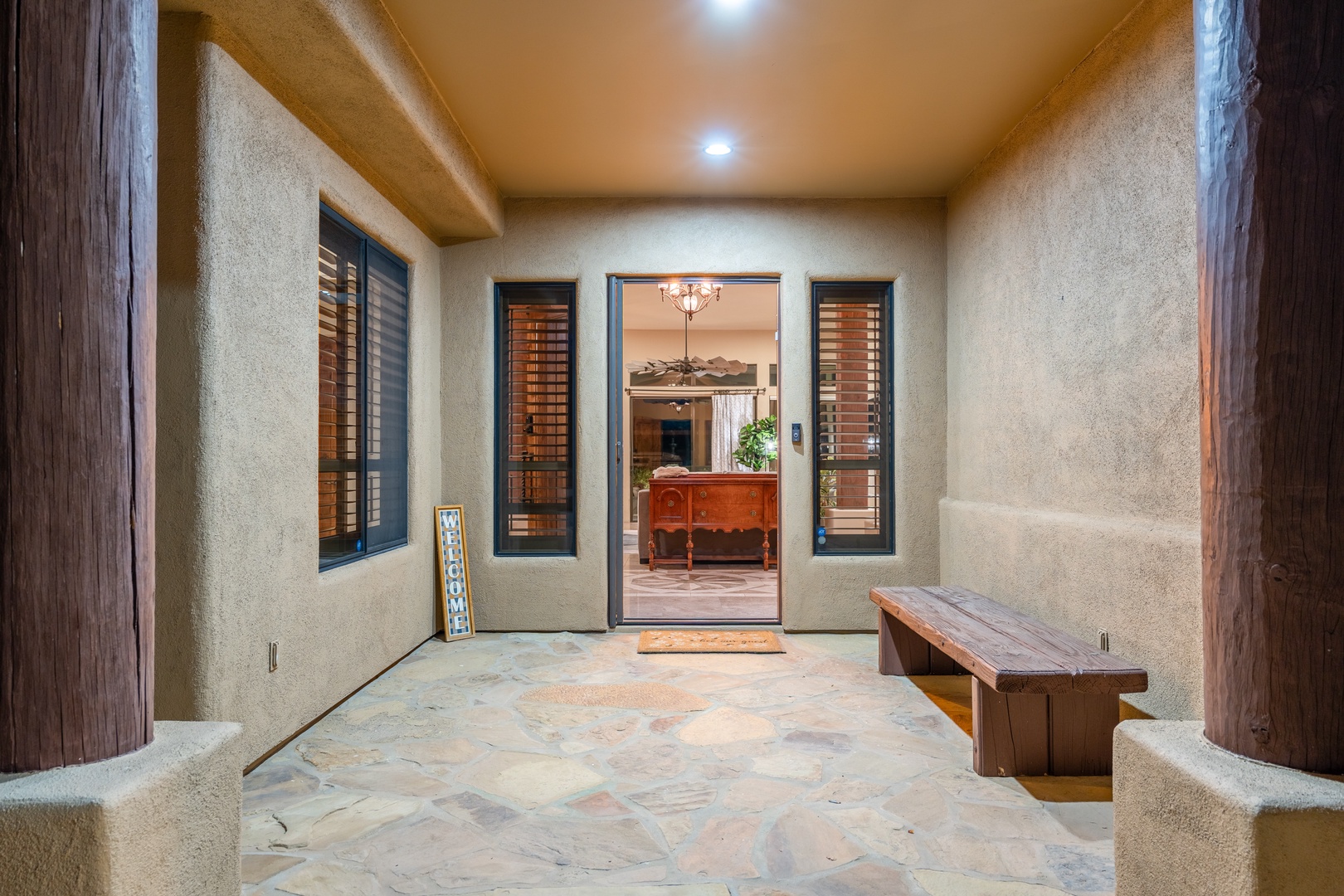 Step into your private courtyard entrance, where warm lighting and a handcrafted wooden bench welcome you home after a day of desert adventures.