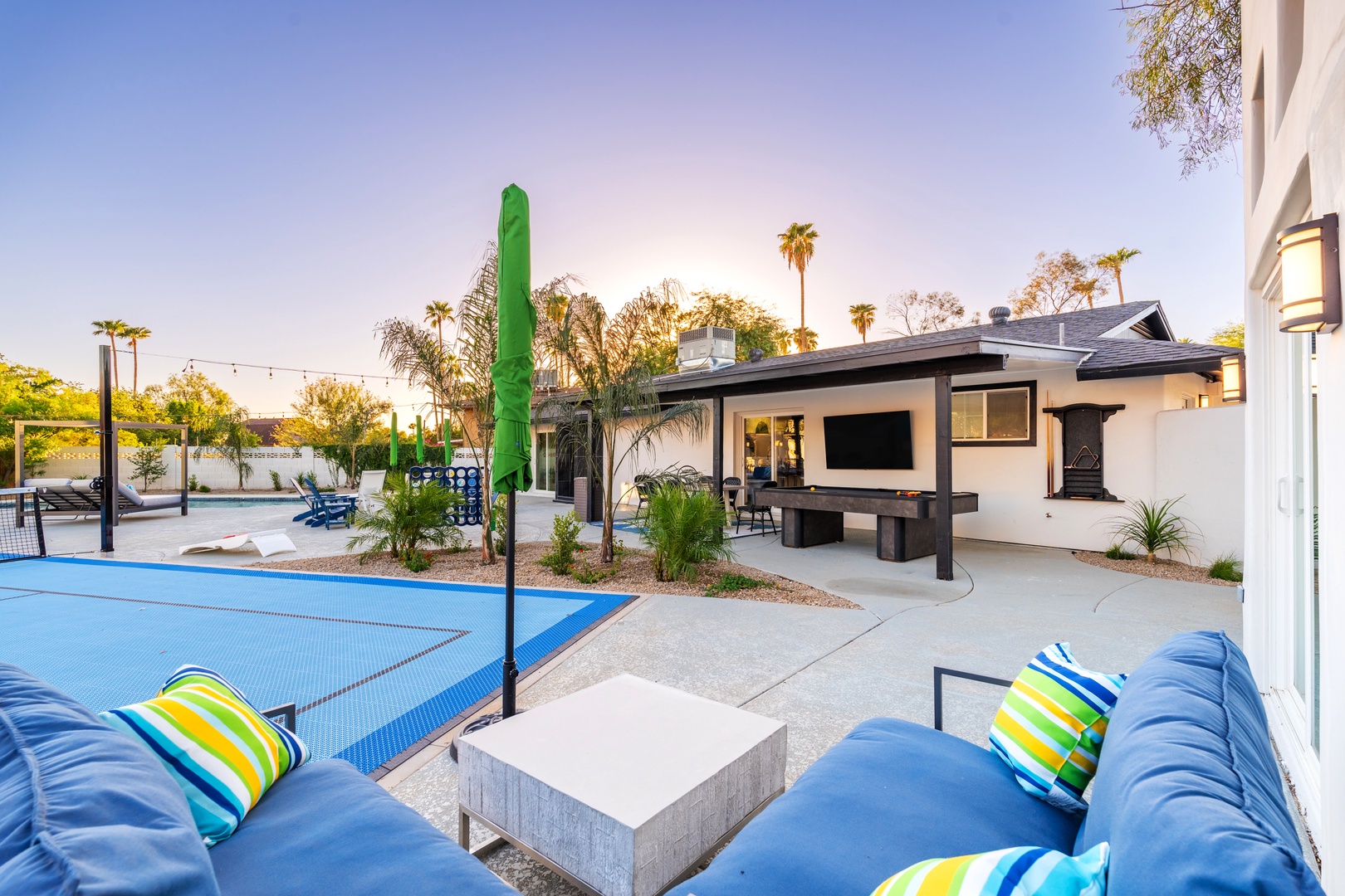 Unwind in your private outdoor retreat with a sport court, cozy seating, and a covered entertainment area—perfect for family fun and relaxation under the palms.