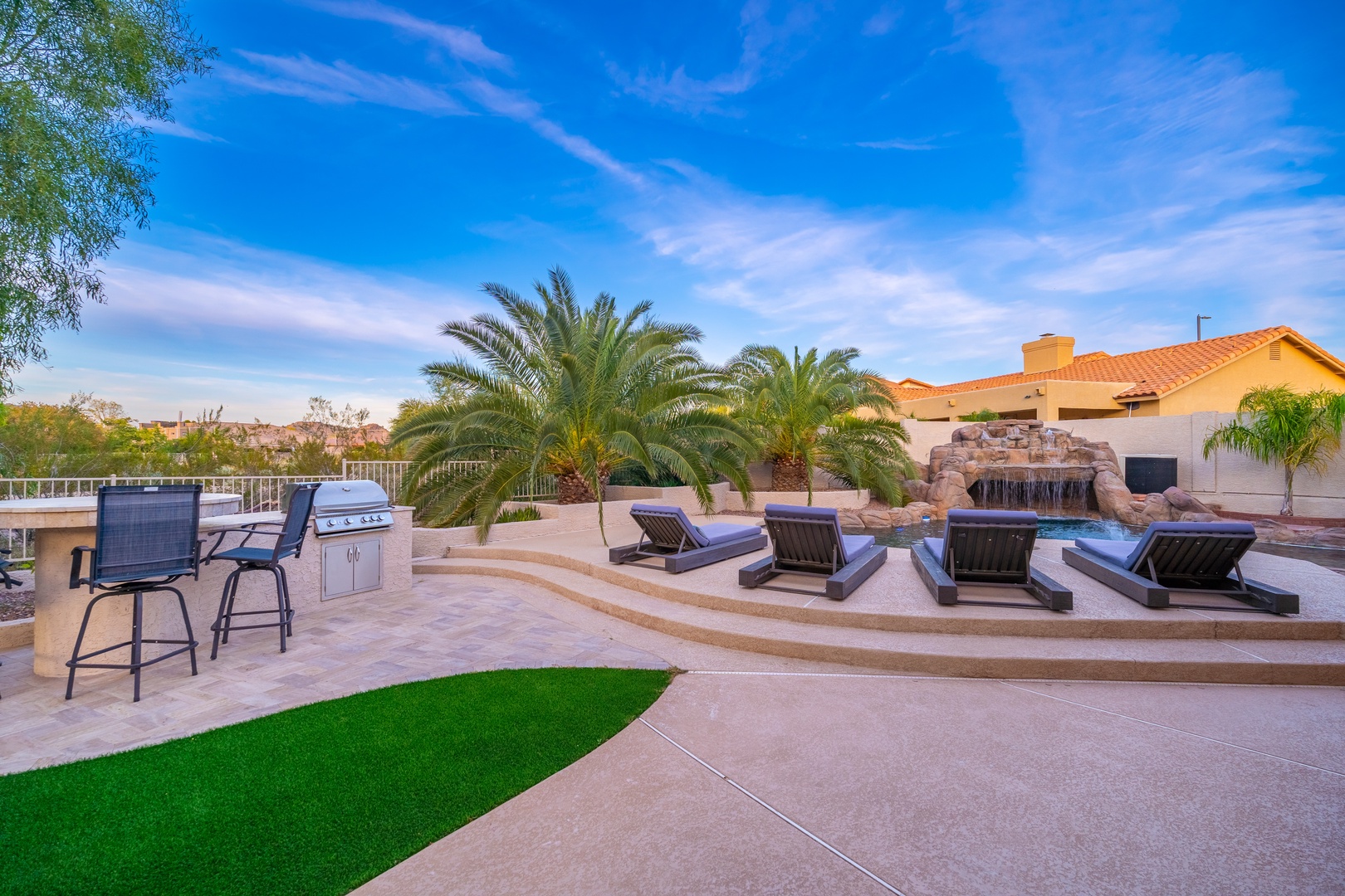 Unwind by your private pool and waterfall, lounge under palm trees, or fire up the built-in grill—this backyard oasis is your sunny escape.