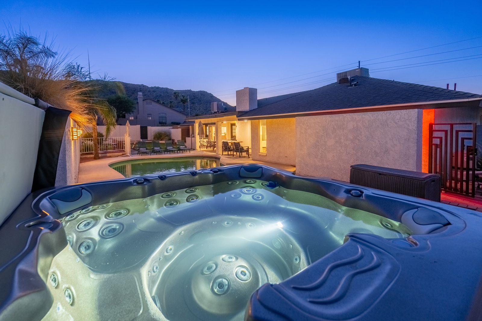 Unwind in your private hot tub overlooking the pool and mountain backdrop, perfect for evening relaxation under the desert sky.