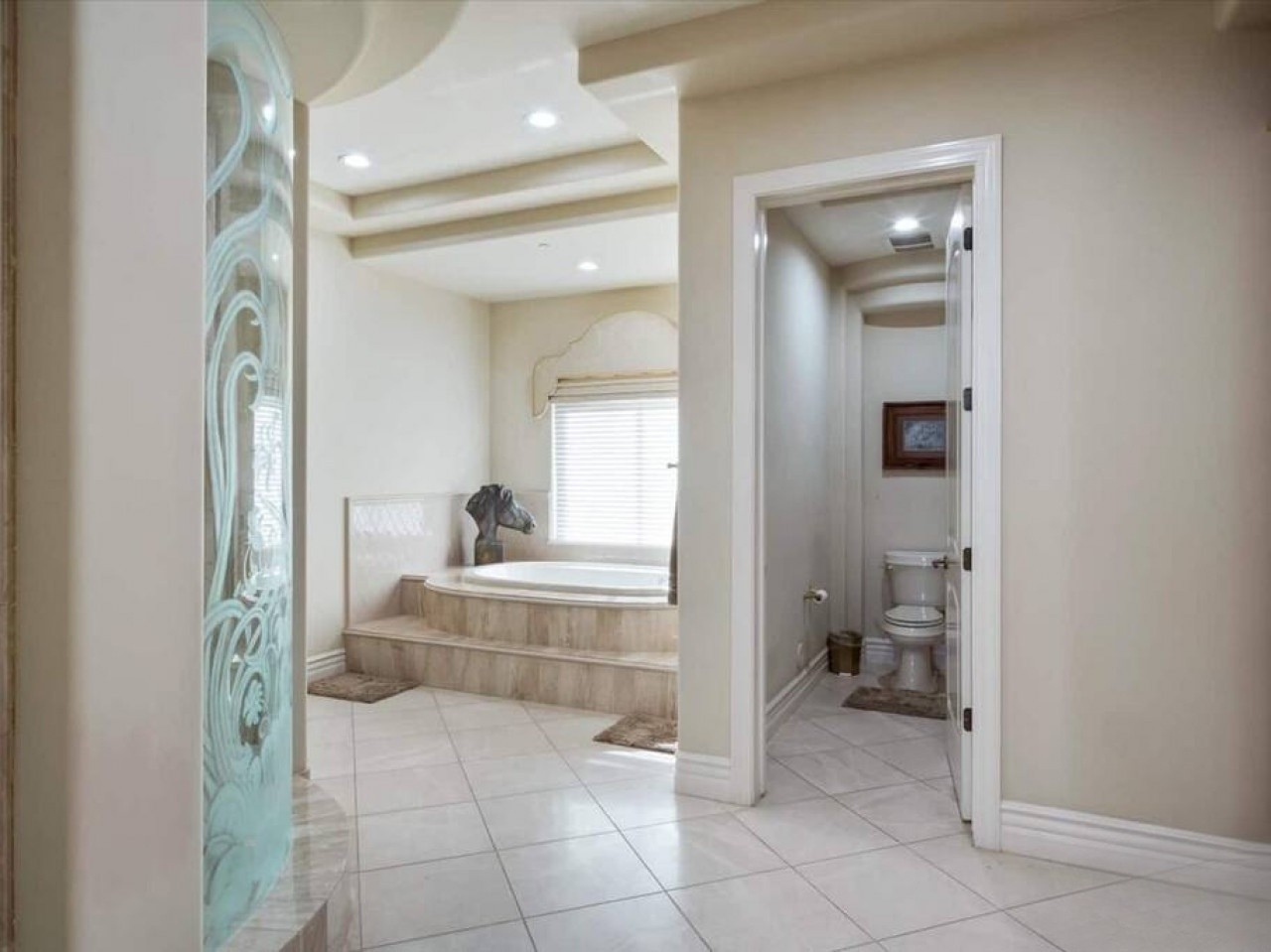 Sink into pure comfort in your private spa-like sanctuary with a luxurious soaking tub beneath natural light, elegant tile flooring, and a spacious layout that invites relaxation.