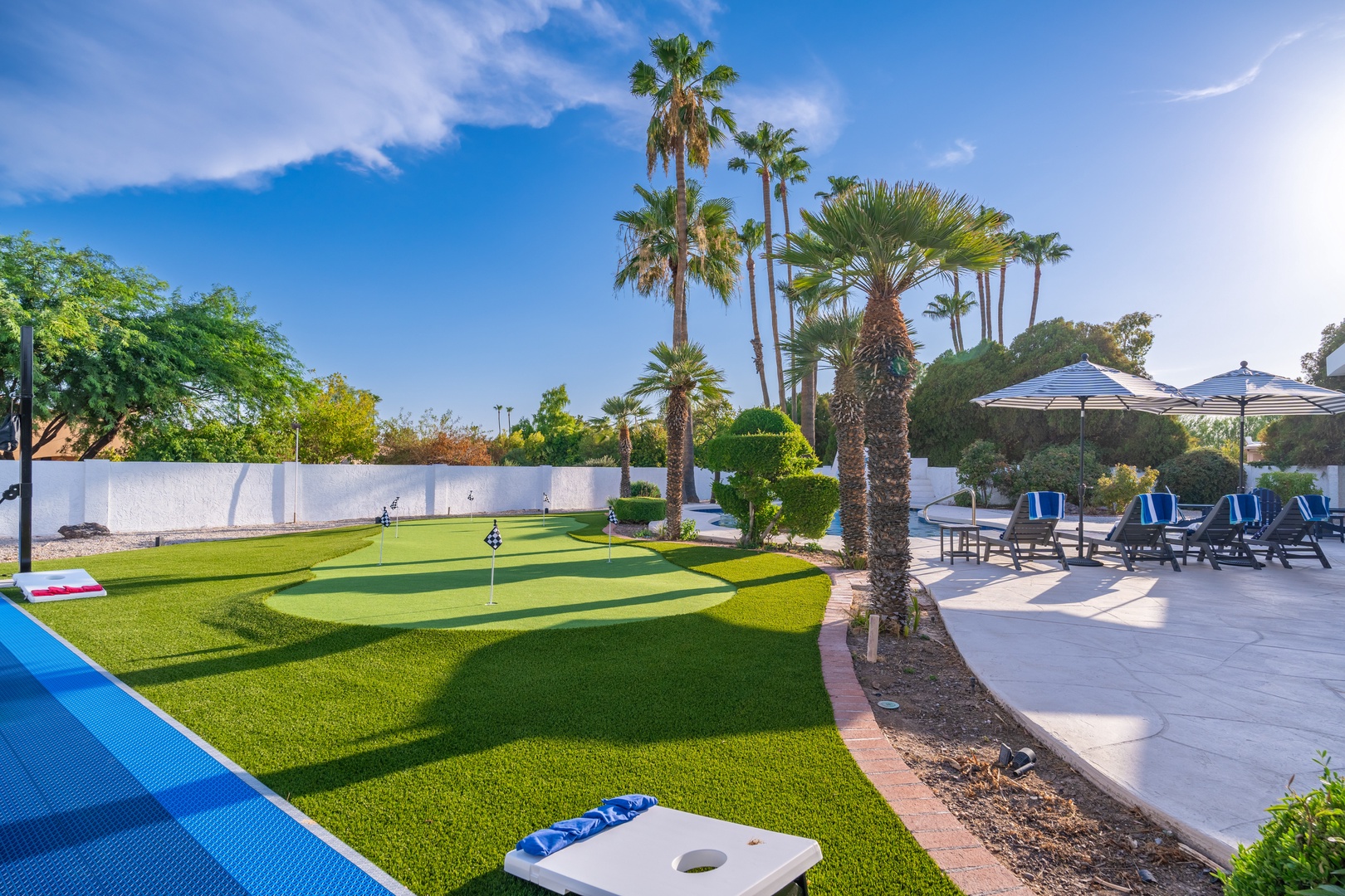 A sun-drenched backyard oasis with a private putting green, cornhole games, and pool loungers surrounded by swaying palms—your perfect spot to unwind and play outdoors all day.