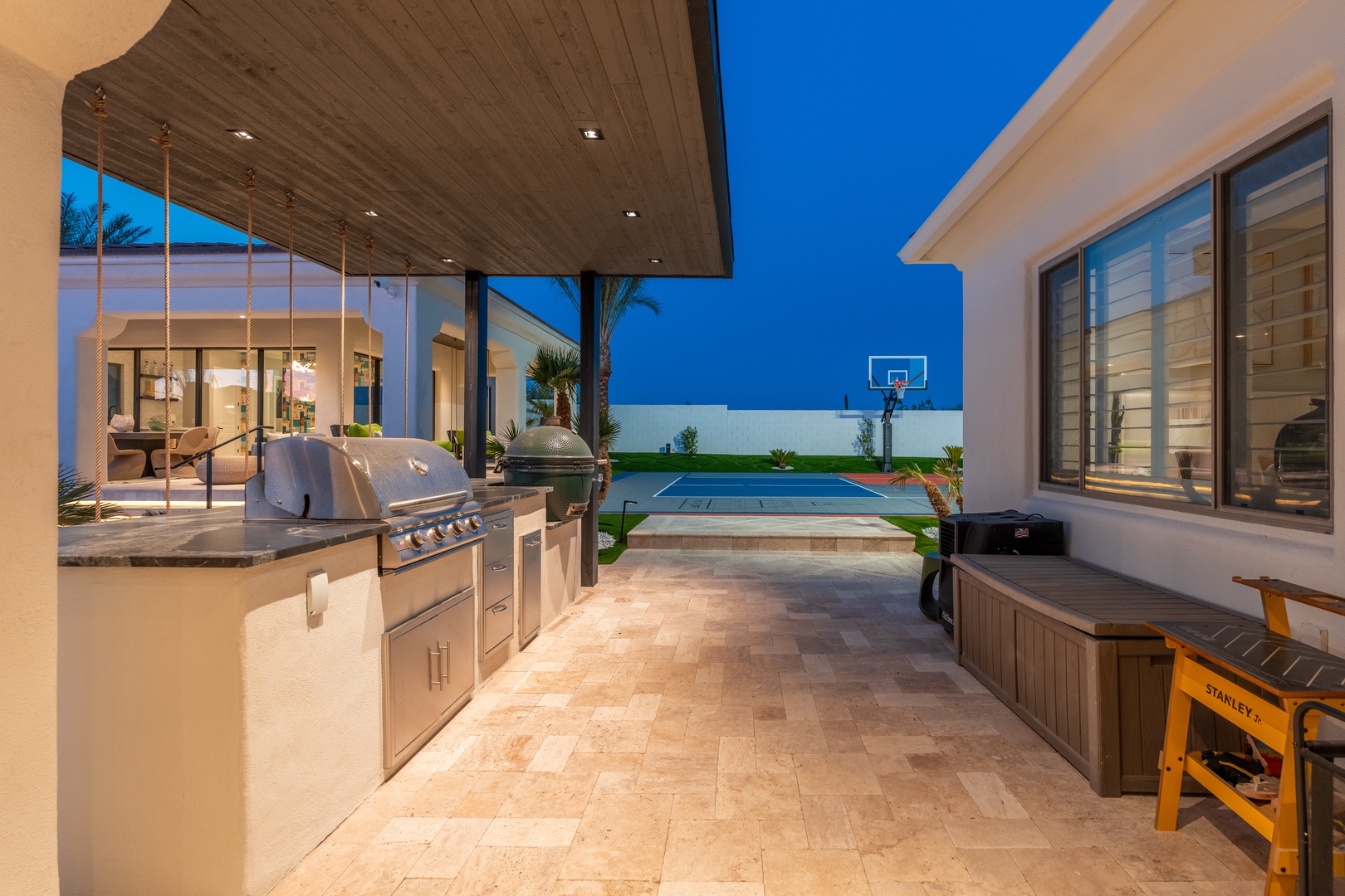 Modern outdoor living awaits with a sleek kitchen, inviting hot tub, and poolside basketball court—your private oasis for fun and relaxation.