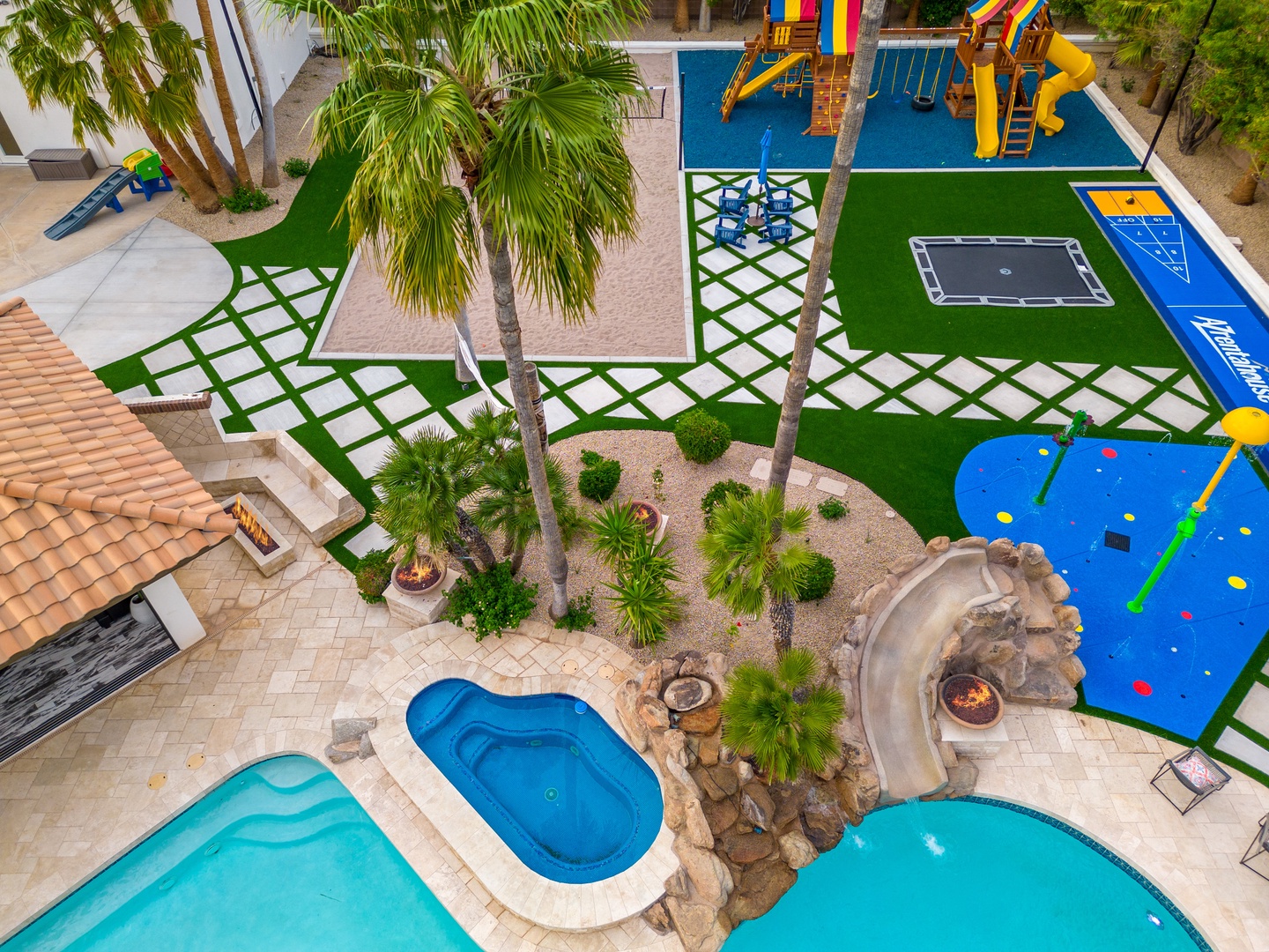 Aerial view of property featuring multiple pools, tropical landscaping, and extensive children's play equipment across vibrant outdoor recreational areas.