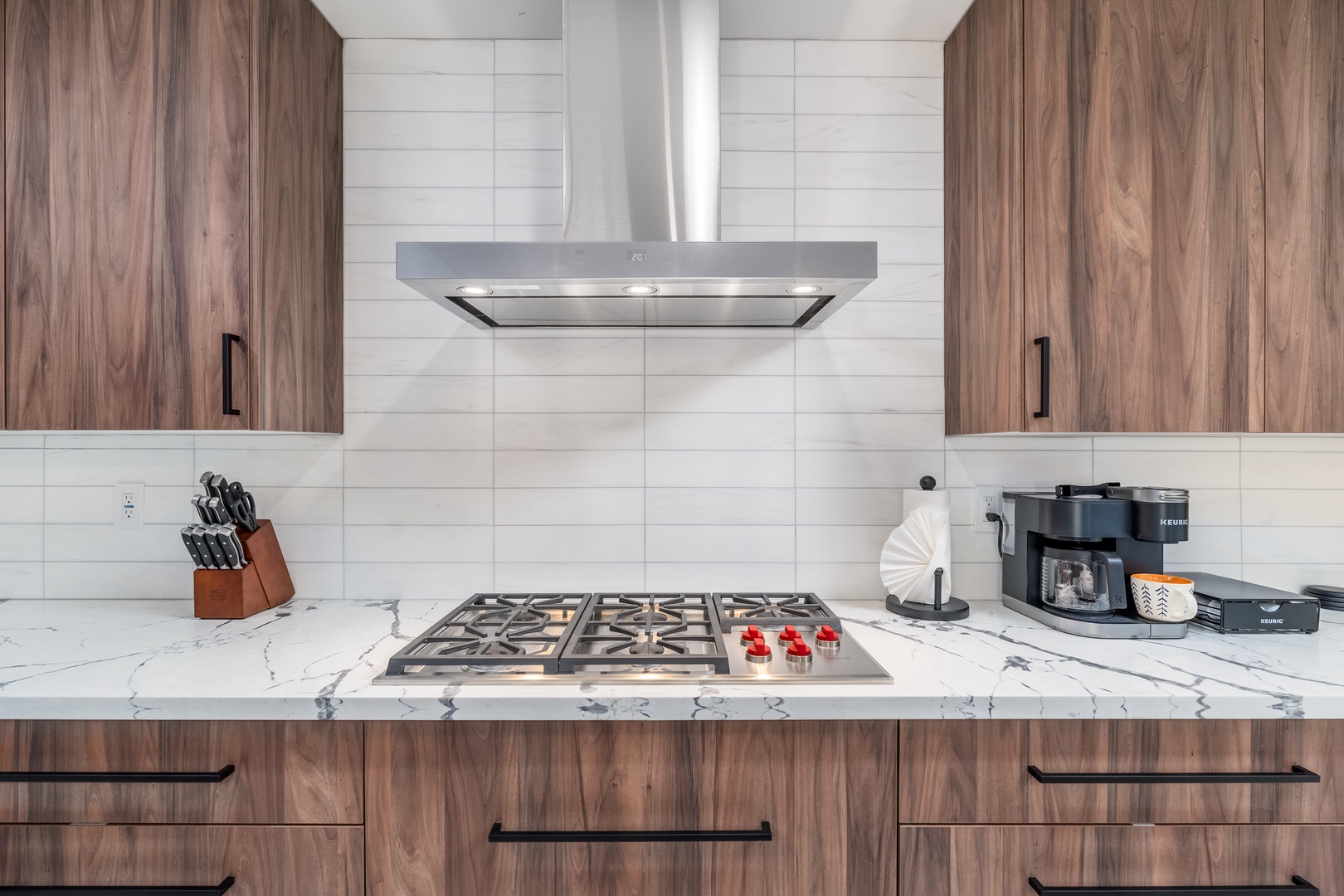 Your chef-worthy kitchen features a pro gas stove, sleek marble counters, and rich walnut cabinetry—perfect for whipping up morning coffee or gourmet meals during your stay.