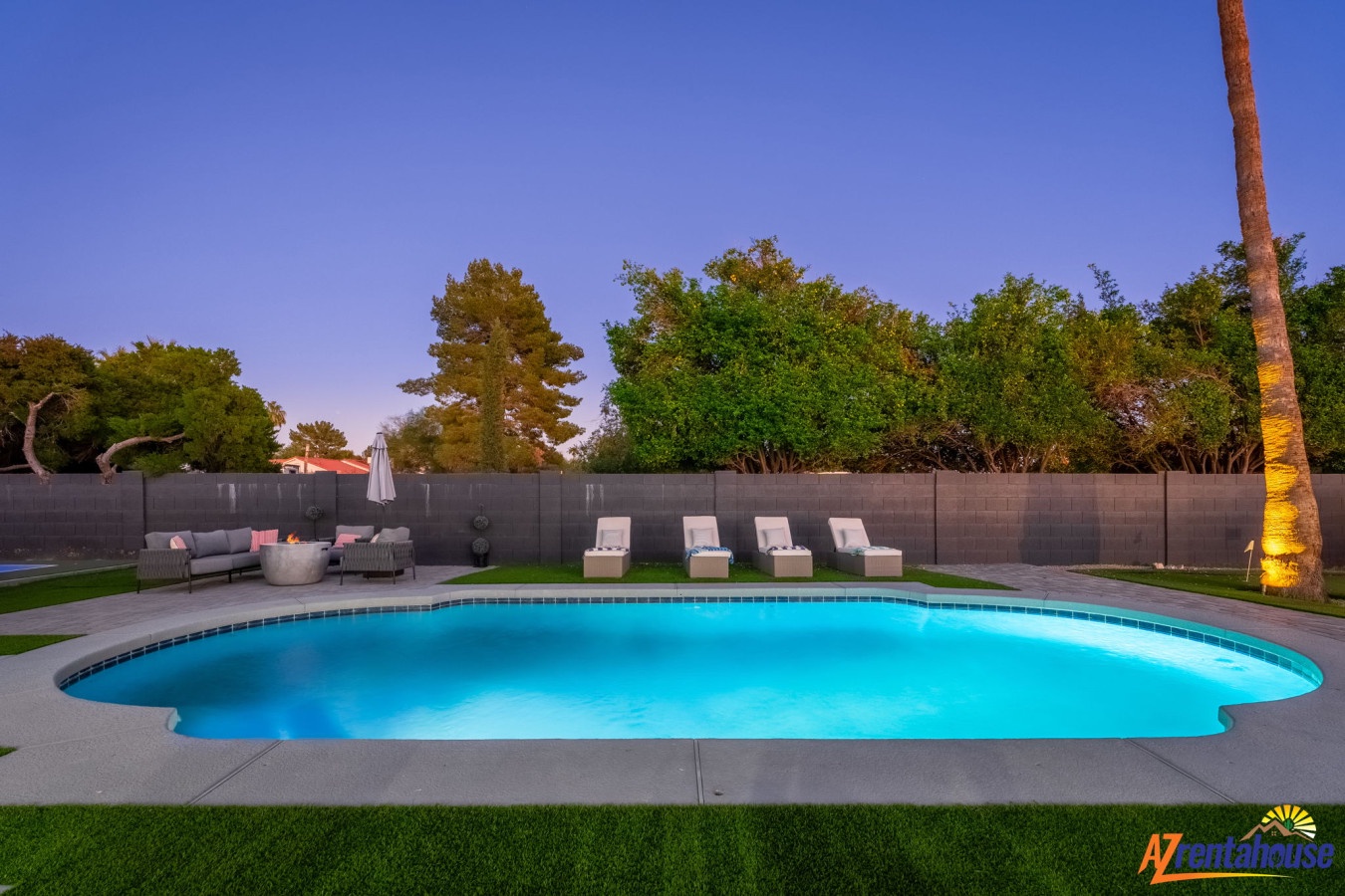 Dusk settles over this pristine pool area with comfortable loungers and modern seating arranged around the illuminated water.