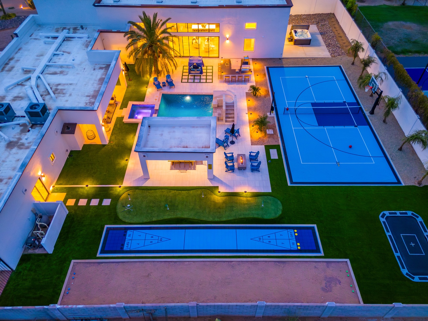 Aerial view of a luxury vacation rental featuring multiple sports courts, a sparkling swimming pool with hot tub, and spacious outdoor entertainment areas perfect for groups.