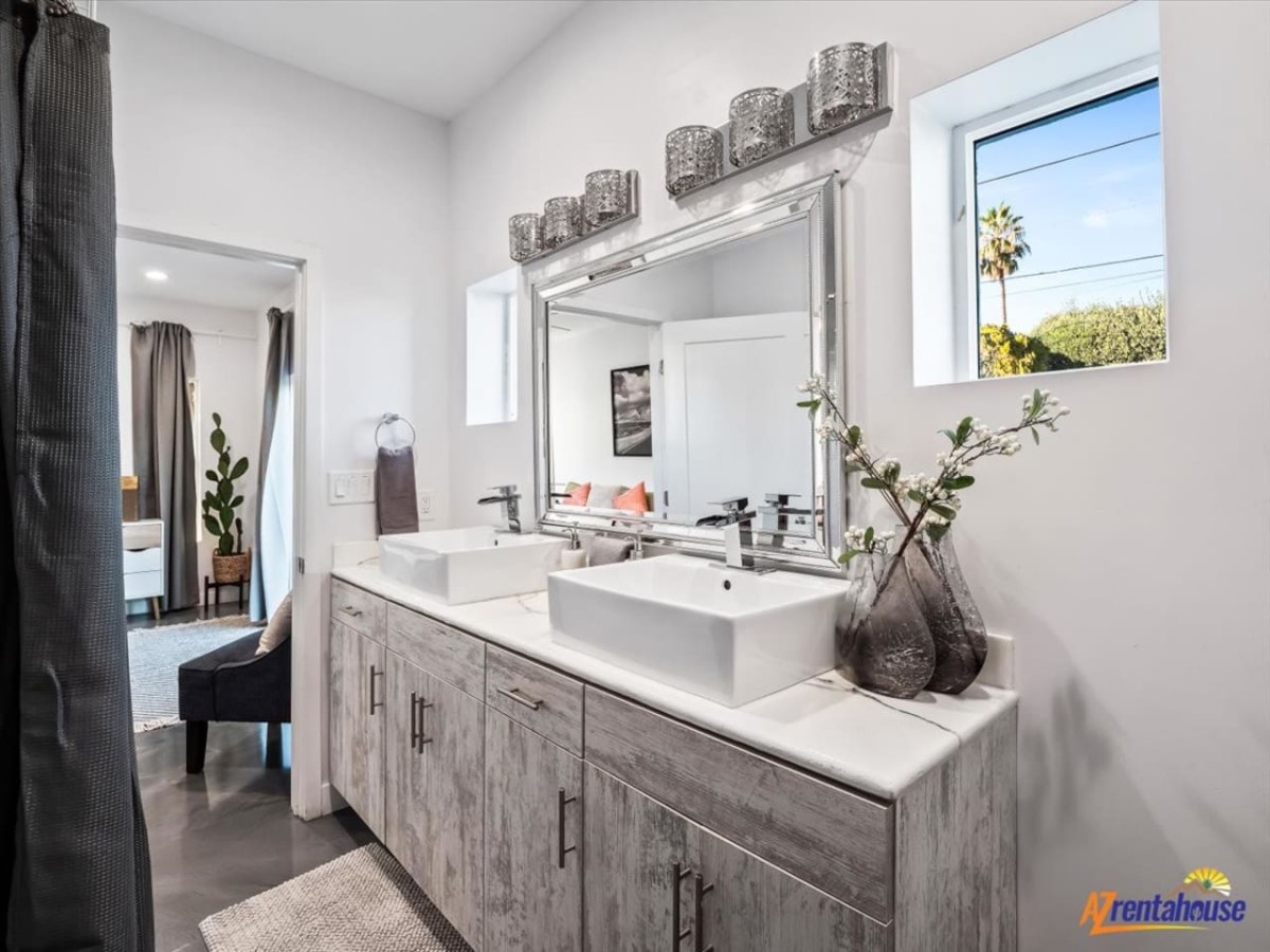 Refresh in your stylish bathroom with dual vessel sinks, modern fixtures, and natural light streaming through the window.