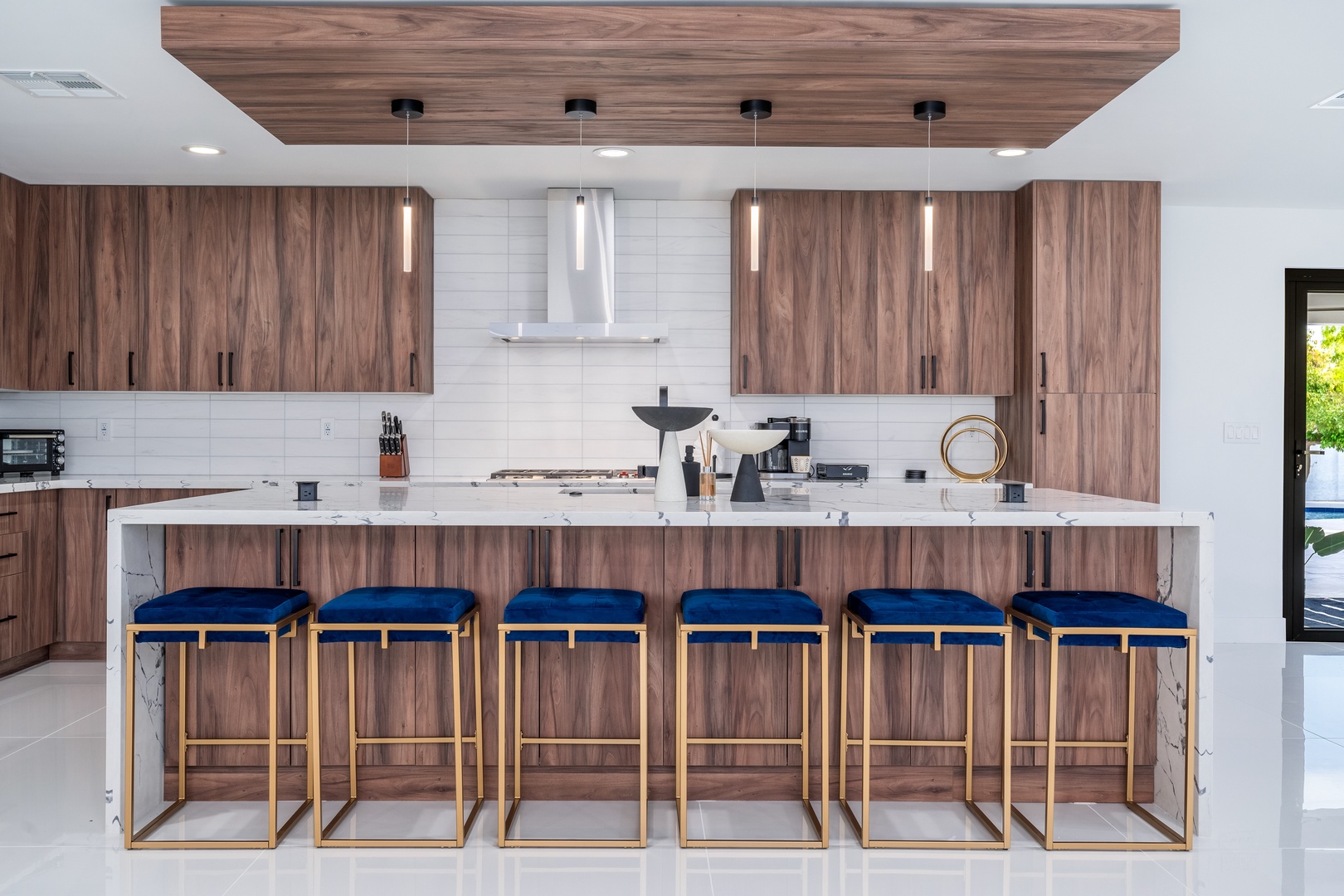 Gather around this stunning chef's kitchen with rich wood cabinetry, expansive marble island, and sleek pendant lighting that sets the stage for your culinary adventures and morning coffee rituals.