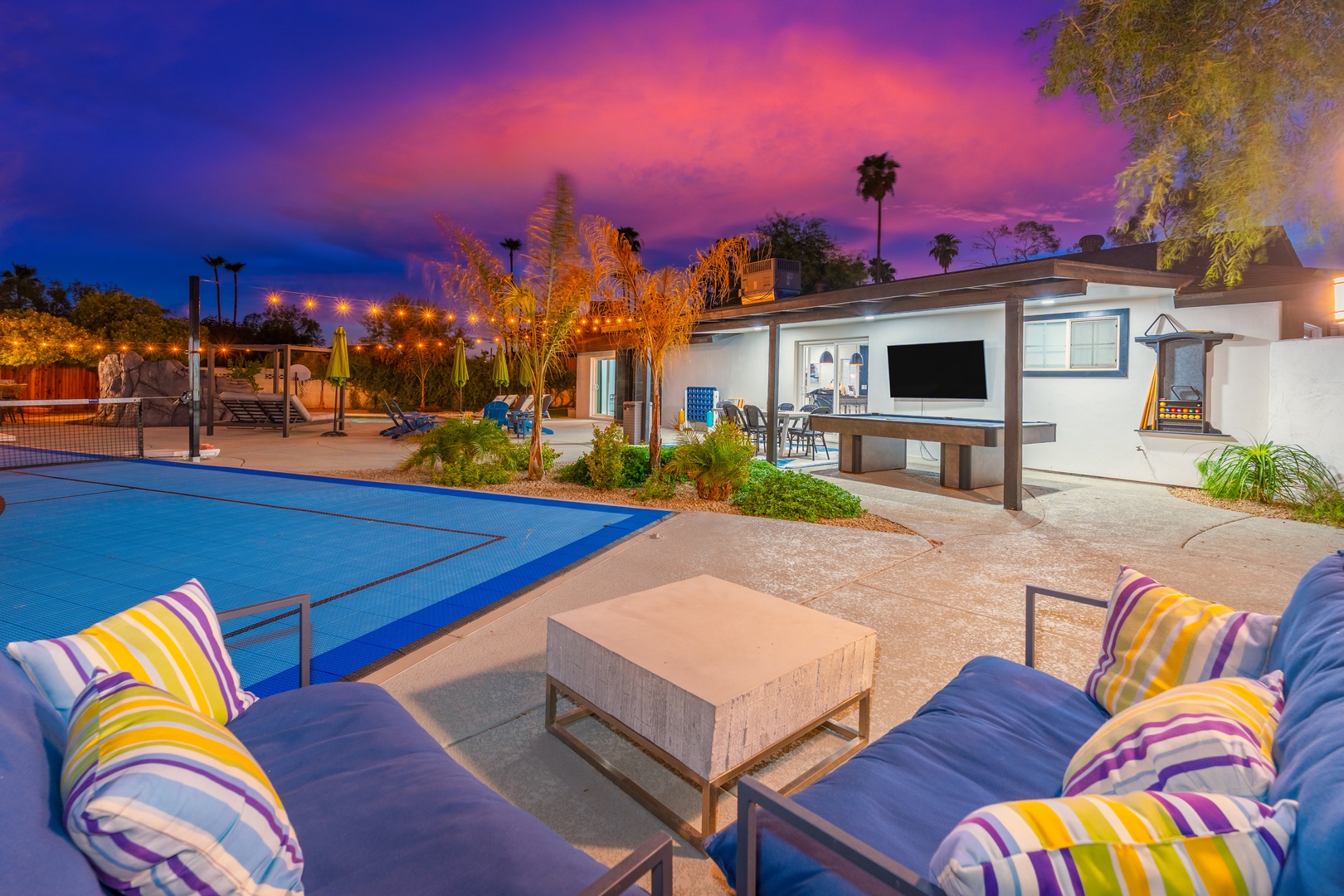 This stunning property features a private pool, tennis court, and spacious outdoor entertainment area set against vibrant sunset skies in a lush garden setting.