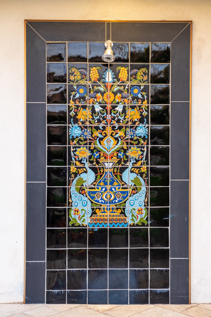 Vibrant handcrafted tile mural greets you at the entrance, adorned with traditional floral motifs in golden yellows, sky blues, and deep navy—a stunning artistic focal point welcoming you to your getaway.