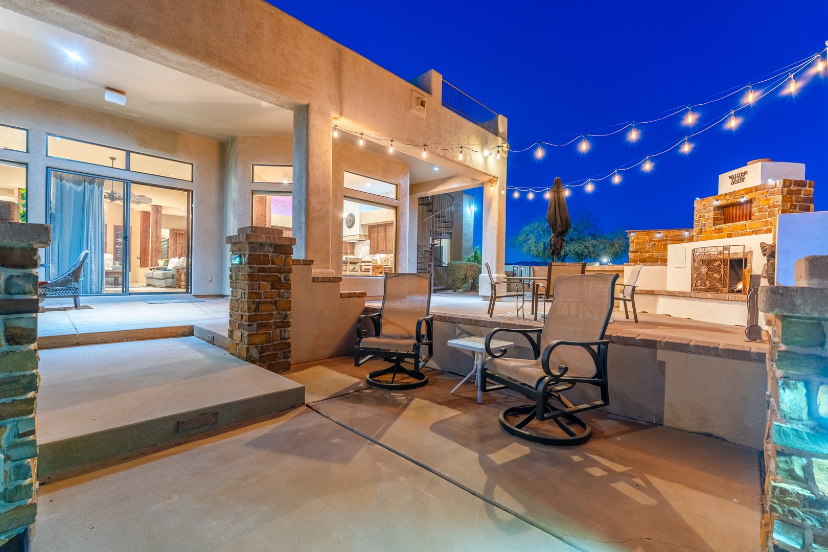 A stunning outdoor patio awaits, complete with string lights overhead and cozy seating—perfect for evening gatherings under the stars with mountains in view.