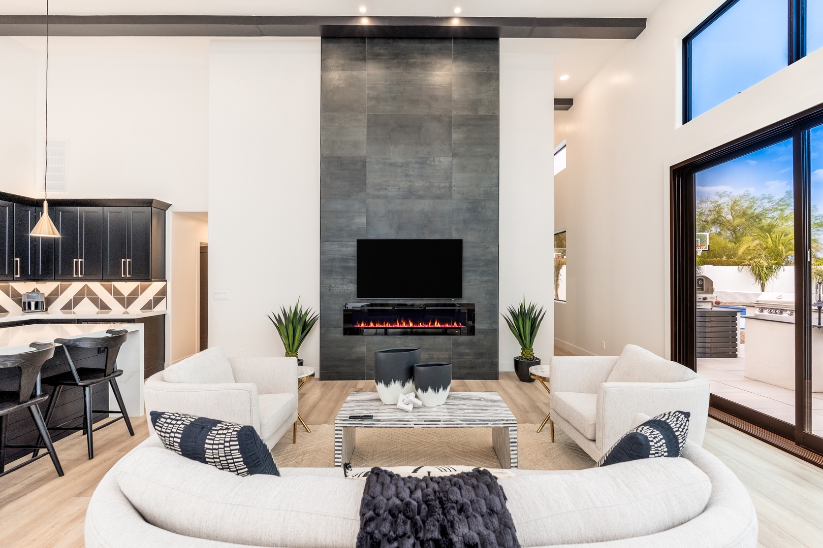 Sink into plush seating in your bright living room, where soaring ceilings, a sleek fireplace, and desert views create a modern sanctuary that feels both airy and warmly inviting.