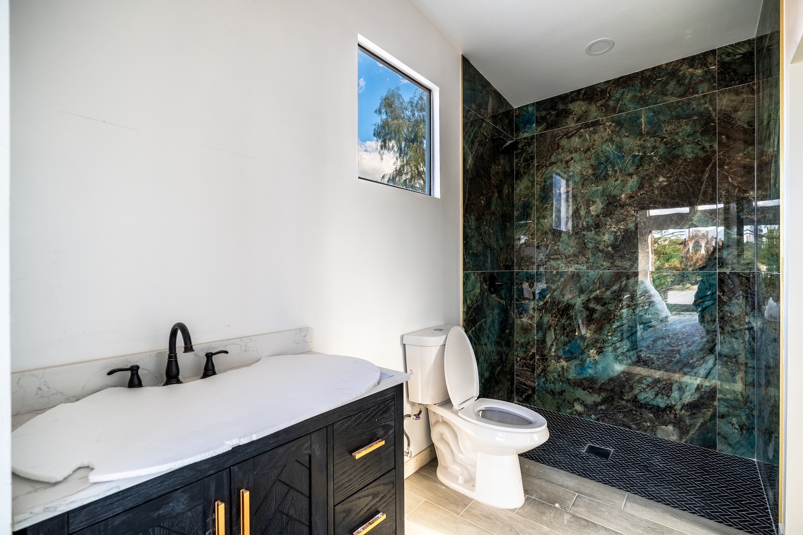 Indulge in spa-like luxury with a deep soaking tub and stunning green marble walk-in shower, where natural light streams in to brighten your morning ritual.