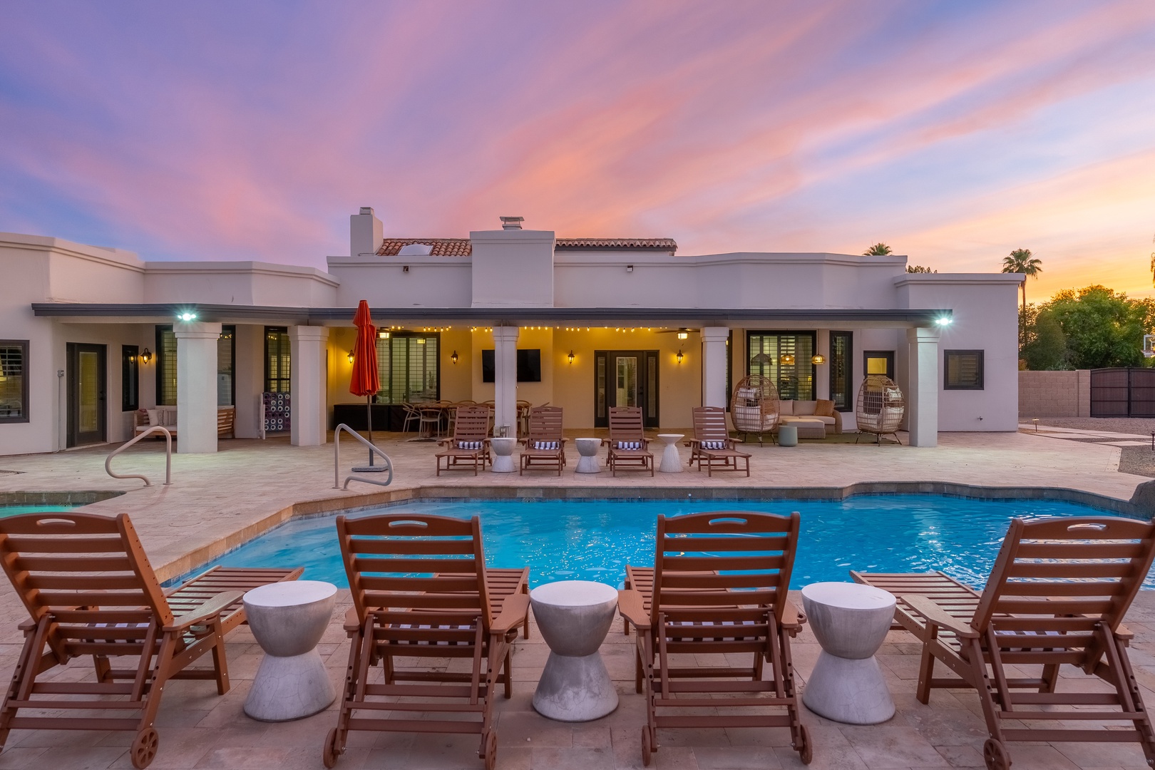 Stunning desert retreat at sunset with expansive pool, loungers, and covered patio—where golden hour meets total relaxation and unforgettable evenings begin.
