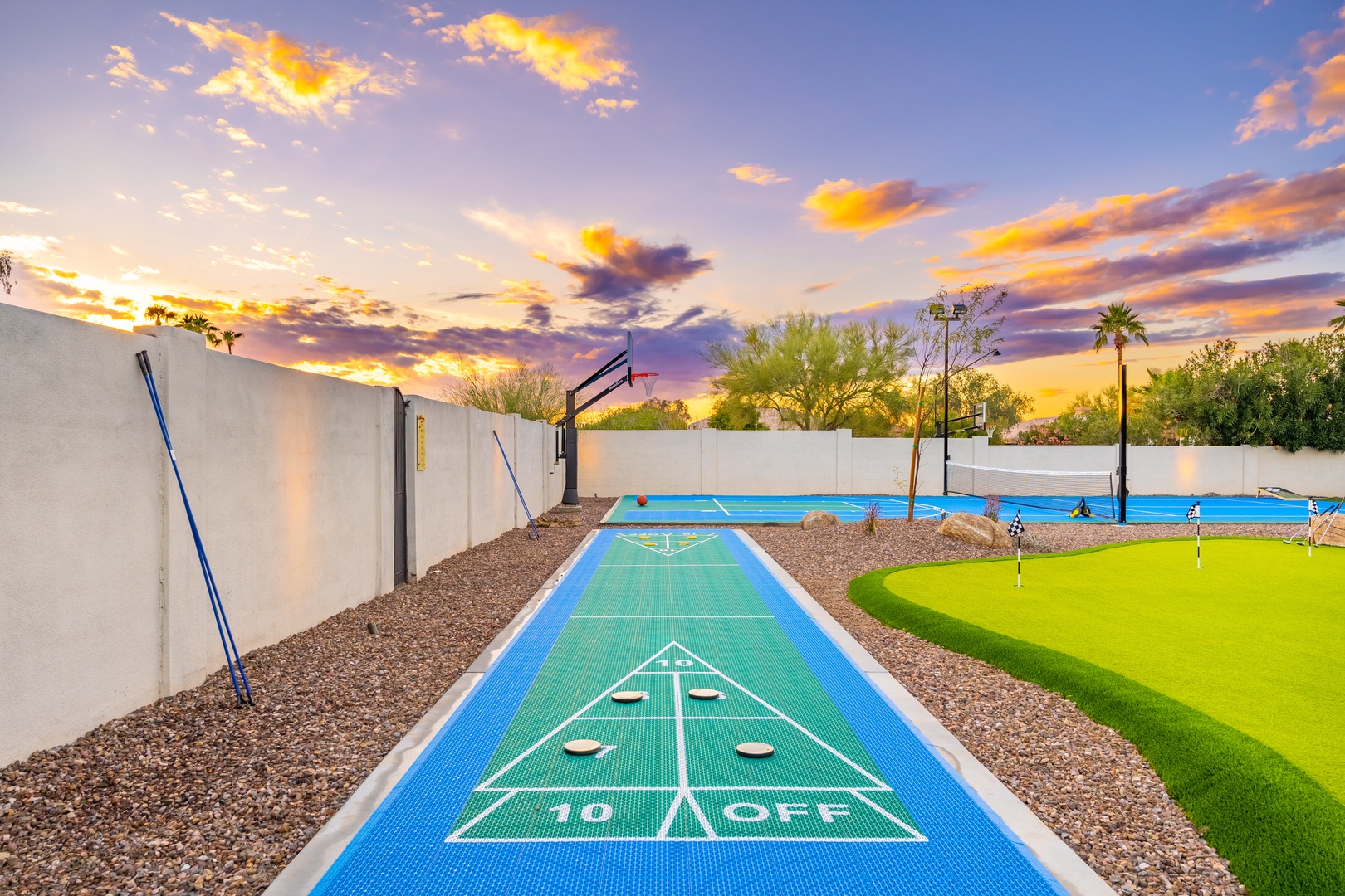 Dramatic sunset illuminates the outdoor recreation area featuring shuffleboard, basketball, swimming pool, and artificial turf putting green.