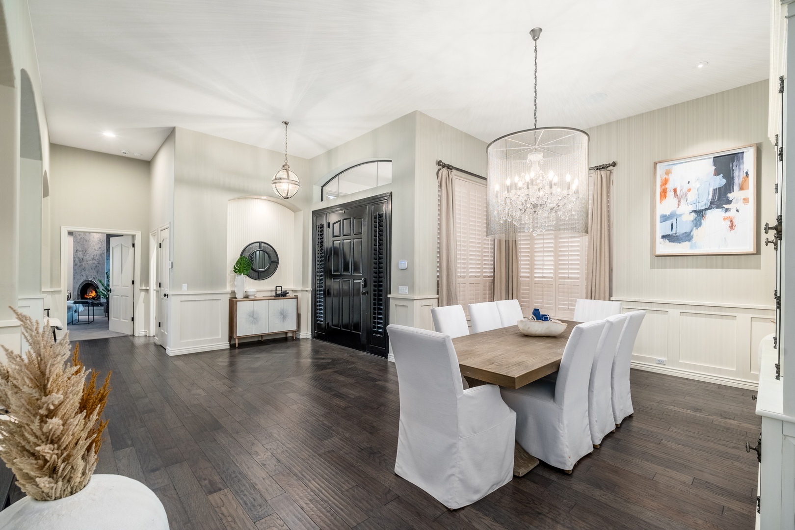 Gather around the elegant dining table beneath a stunning chandelier—your space for memorable meals together. Natural light pours in through tall windows, creating a welcoming ambiance perfect for relaxing conversation.