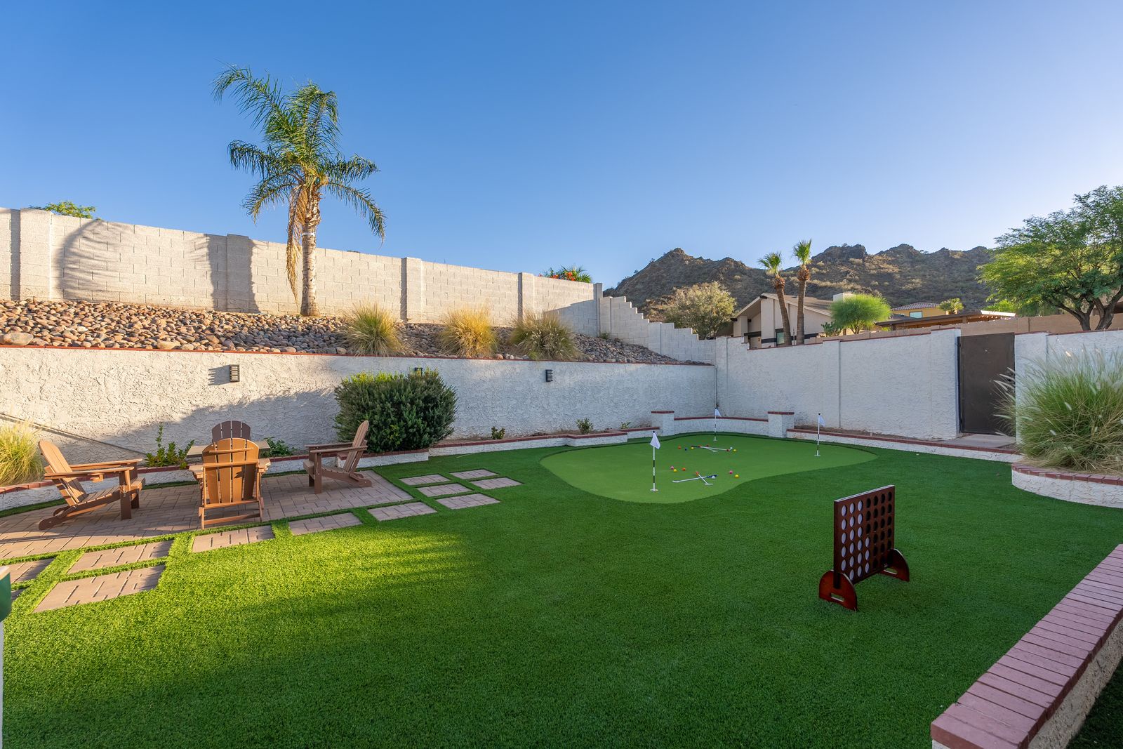 This private backyard features a mini putting green and games, framed by desert landscaping and mountain views—ideal for outdoor relaxation and fun.