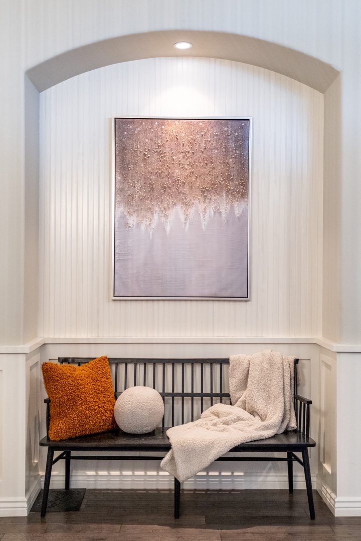 Settle into your cozy reading nook beneath a stunning art piece. Plush throws and textured pillows invite you to unwind in this peaceful alcove designed for quiet moments.