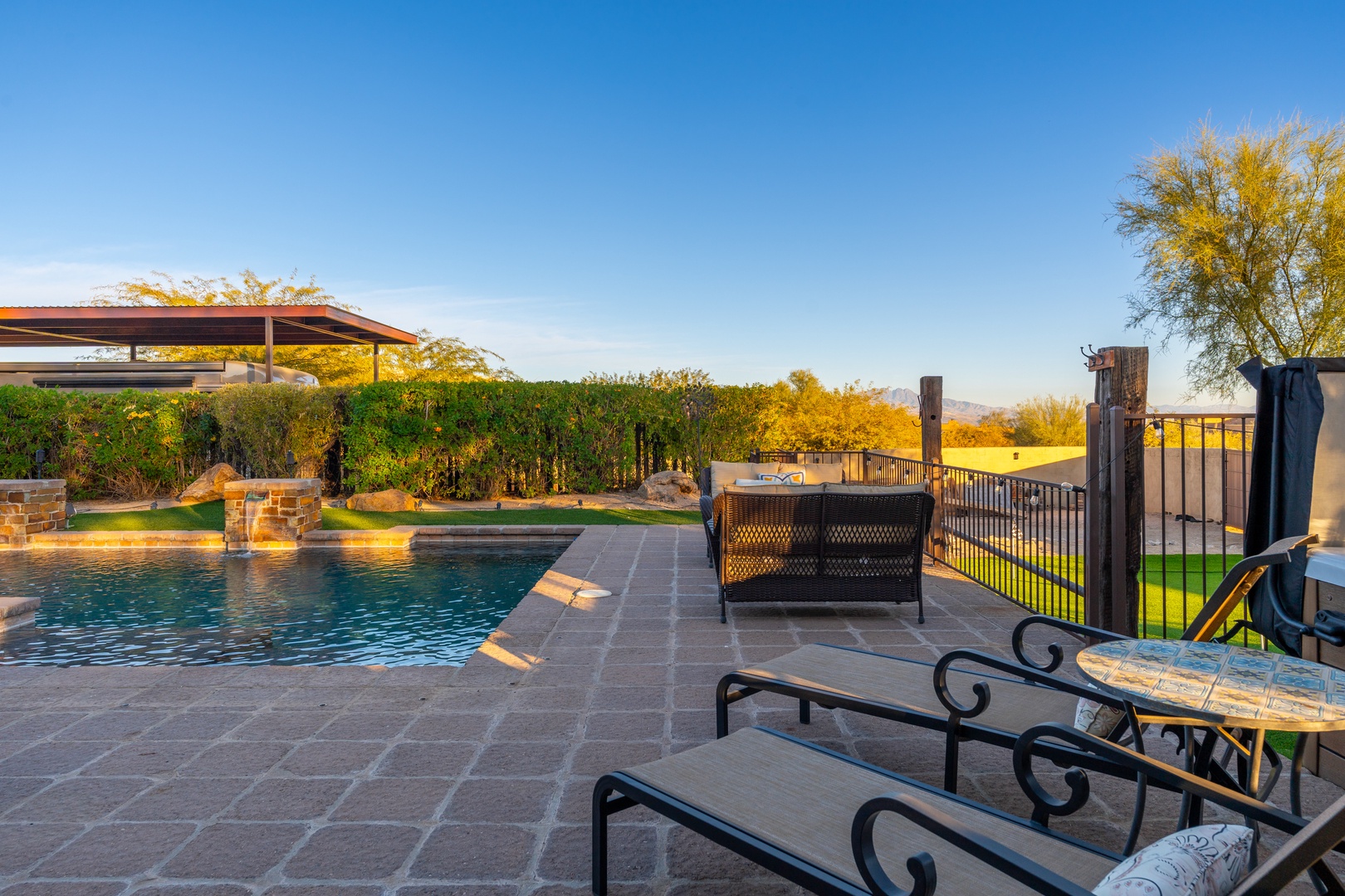 Sparkling pool and spacious patio overlook lush gardens and rolling greens, framed by vibrant trees catching golden light—an inviting escape for relaxation and outdoor enjoyment.