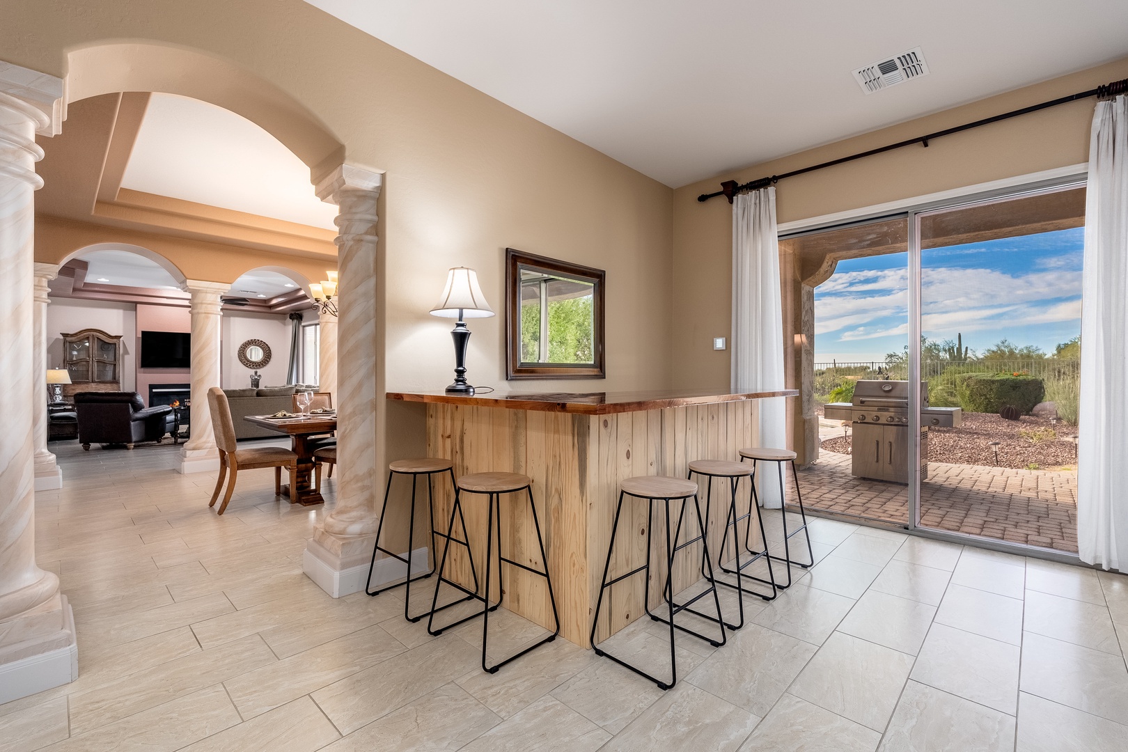 Picture yourself gathering with loved ones at this inviting bar, where warm desert light pours through sliding doors and conversations flow as naturally as the open layout.